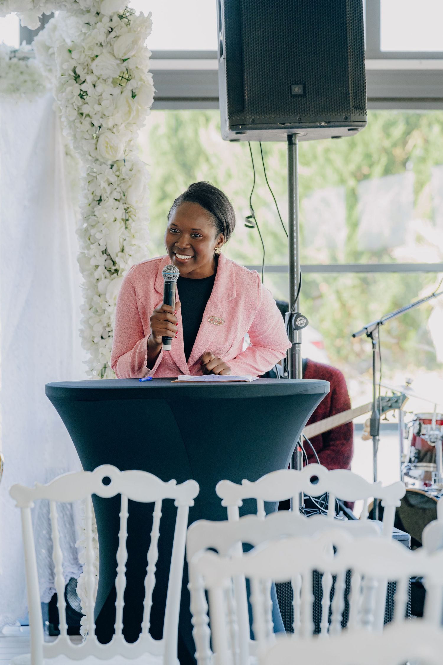 A pianist performs in a pink blazer at an elegant event with white floral decorations.