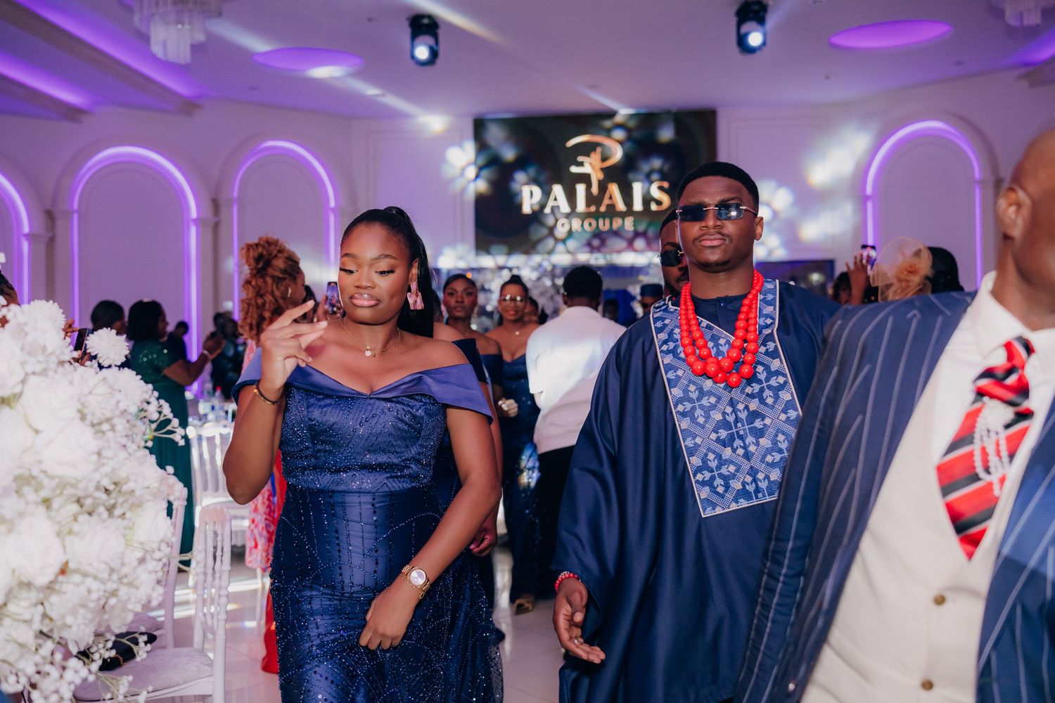 Guests in traditional and modern formal attire celebrate at an elegant wedding reception.