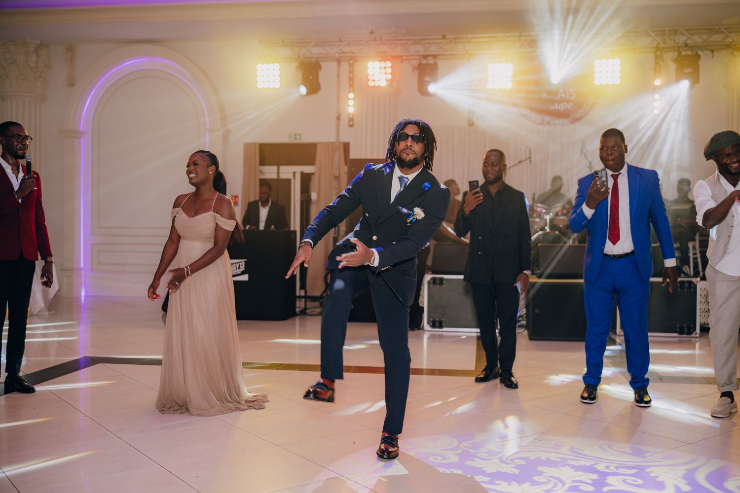 Wedding party dancing together on a purple-lit dance floor during a lively reception celebration.