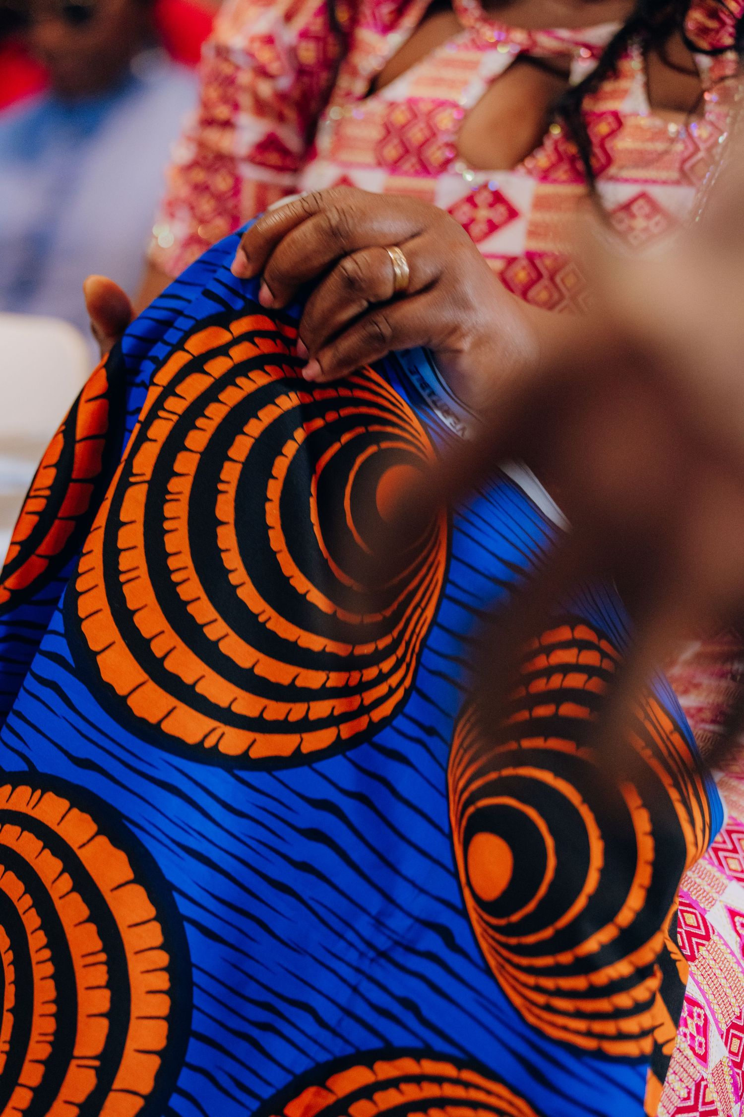Traditional African attire featuring vibrant blue fabric with orange spiral patterns during a celebration.