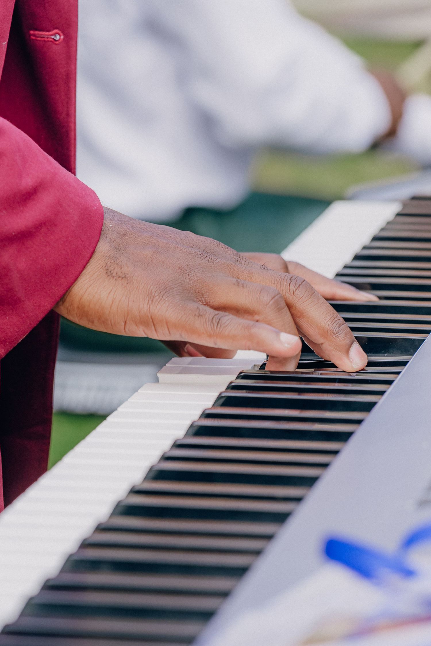 Close-up of hands playing piano keys during an outdoor performance.