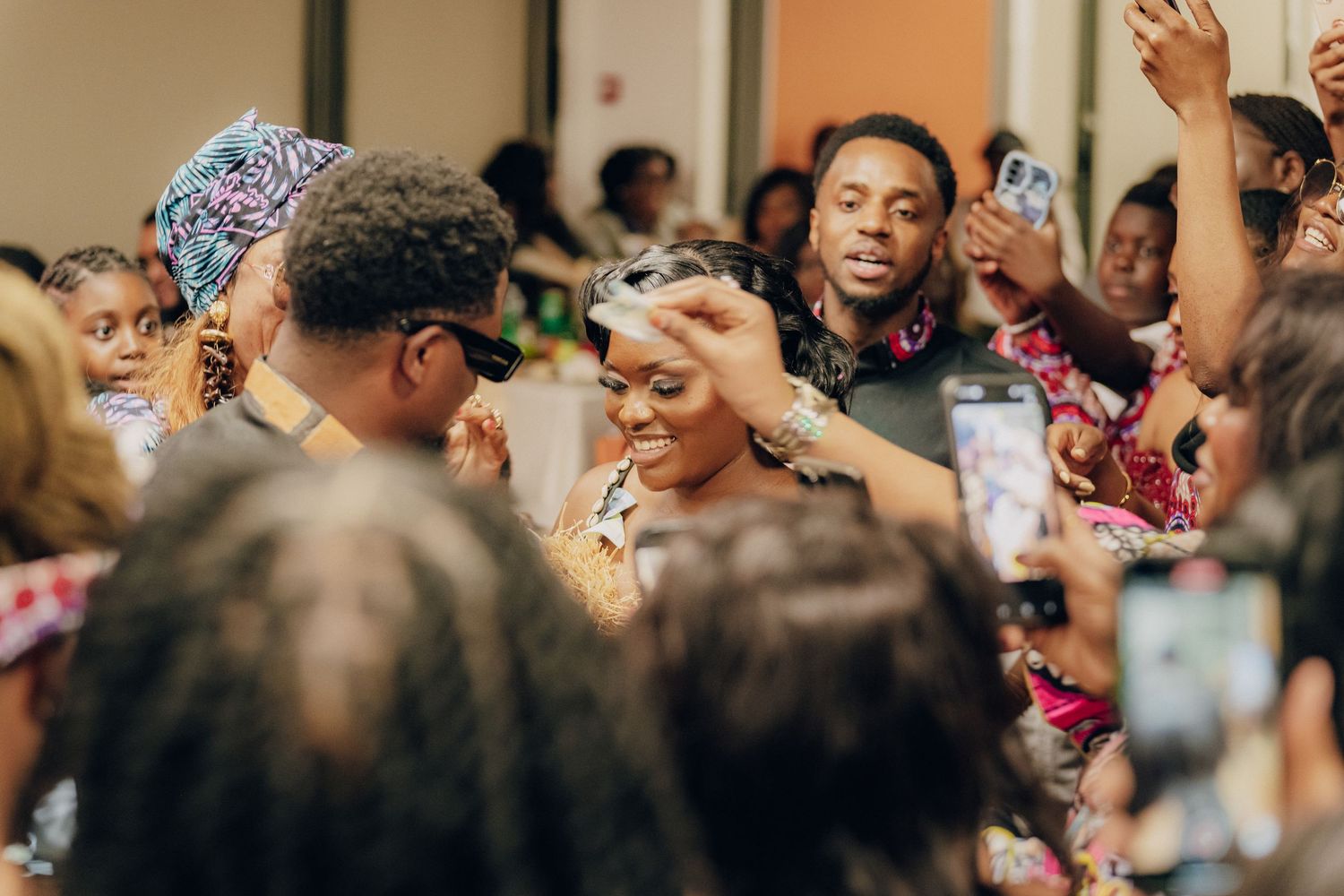 Energetic crowd celebrating at a lively indoor party with raised hands and joyful expressions.