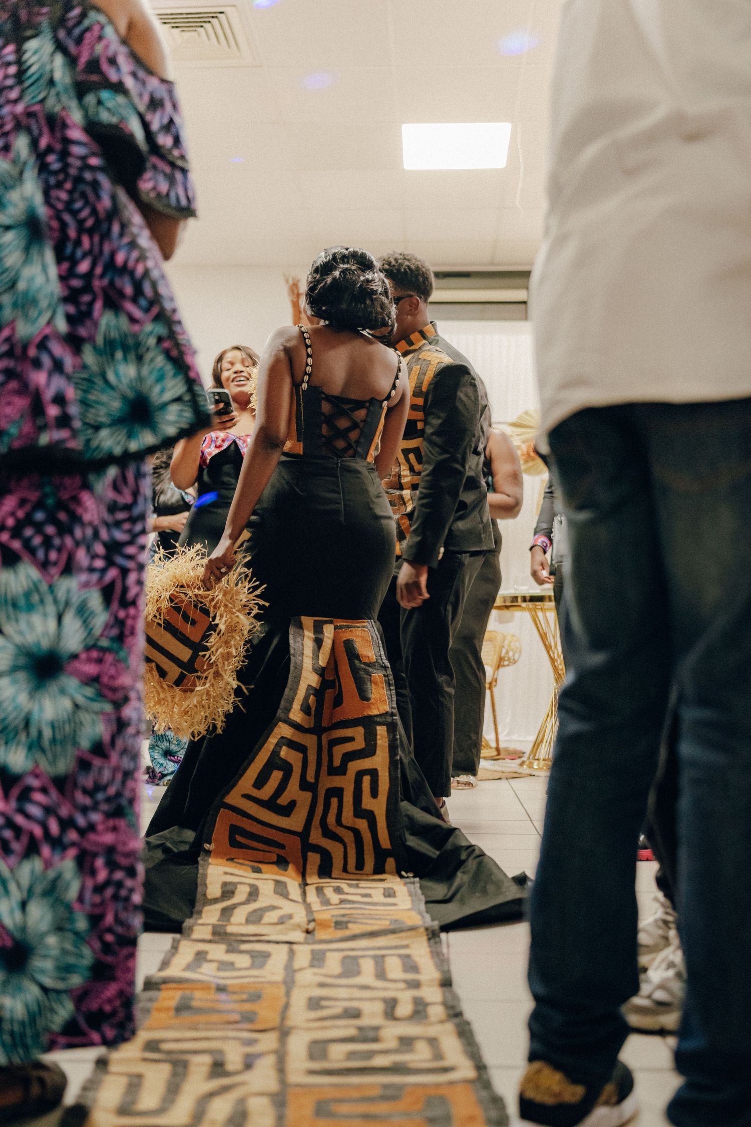 People gathered at an event walking on a patterned carpet in formal attire.