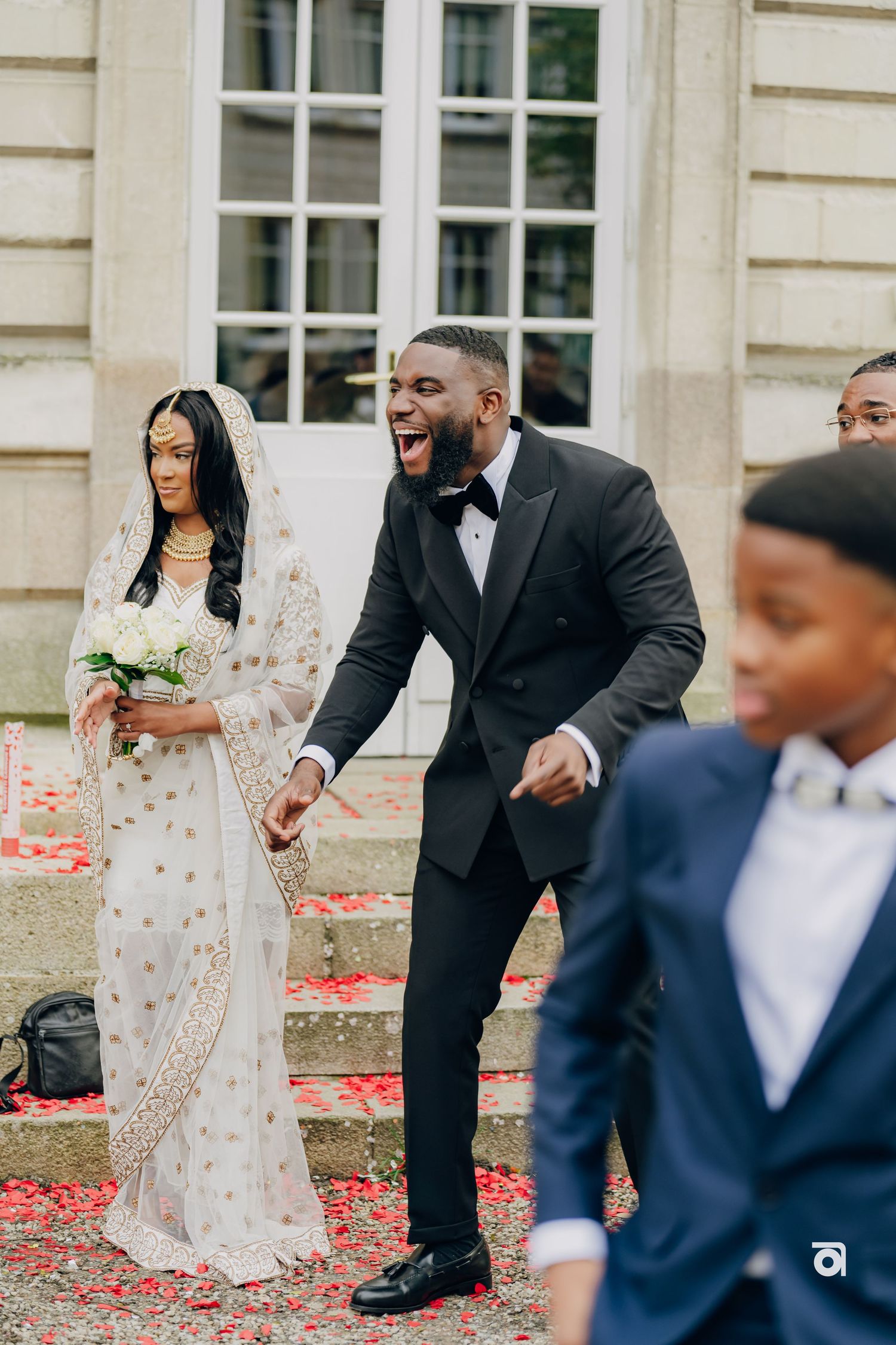 A joyous outdoor wedding celebration with confetti scattered on red carpet.