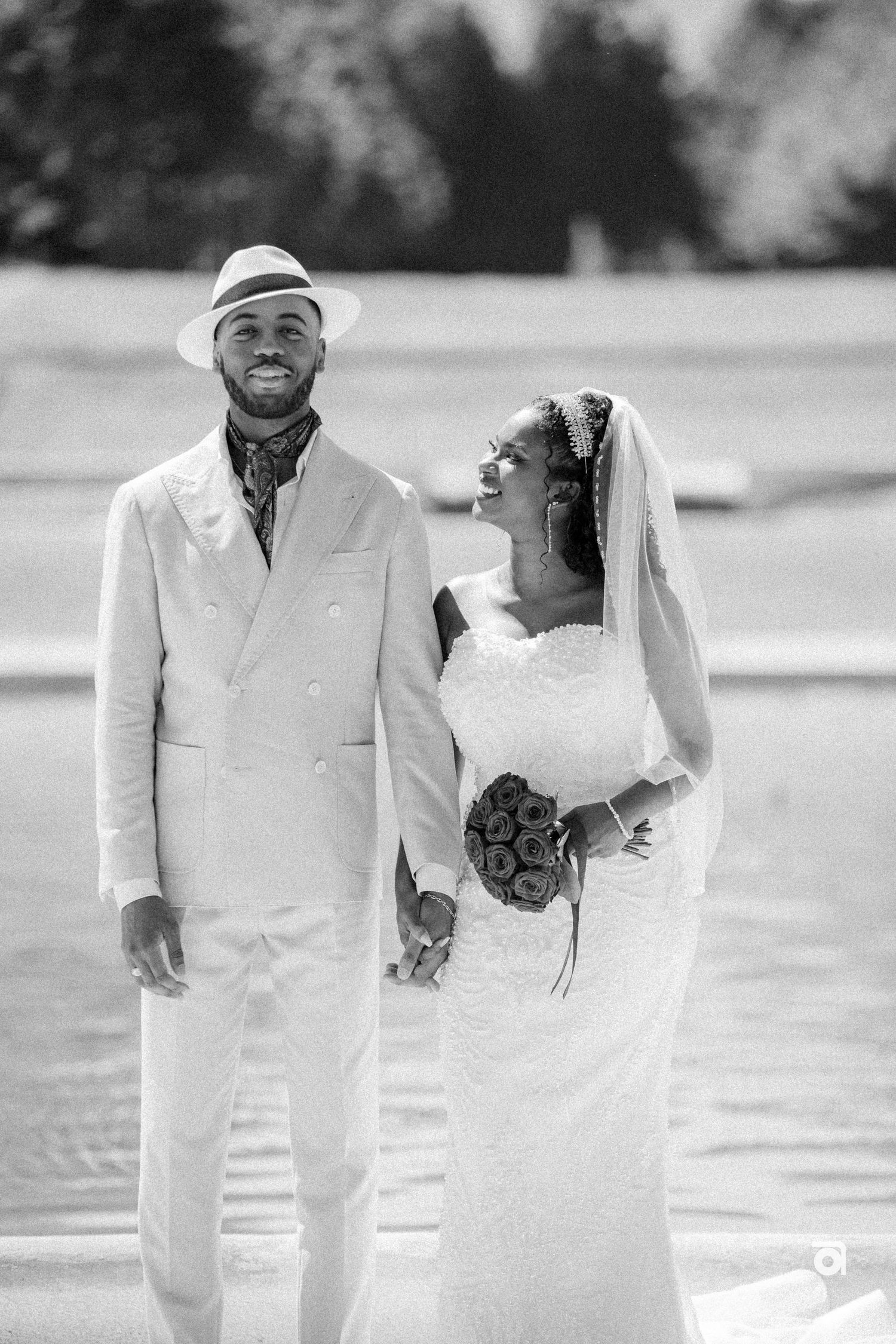 Black and white photo of newlyweds sharing a candid moment together in formal wedding attire.