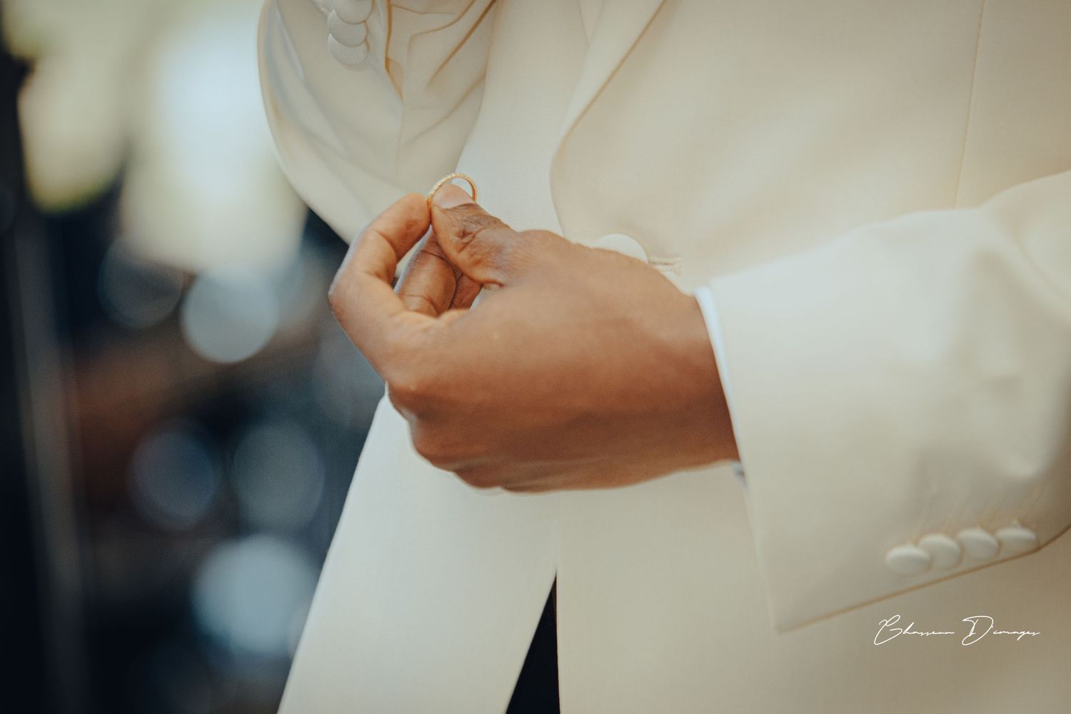 Close-up detail of hands adjusting formal white attire.
