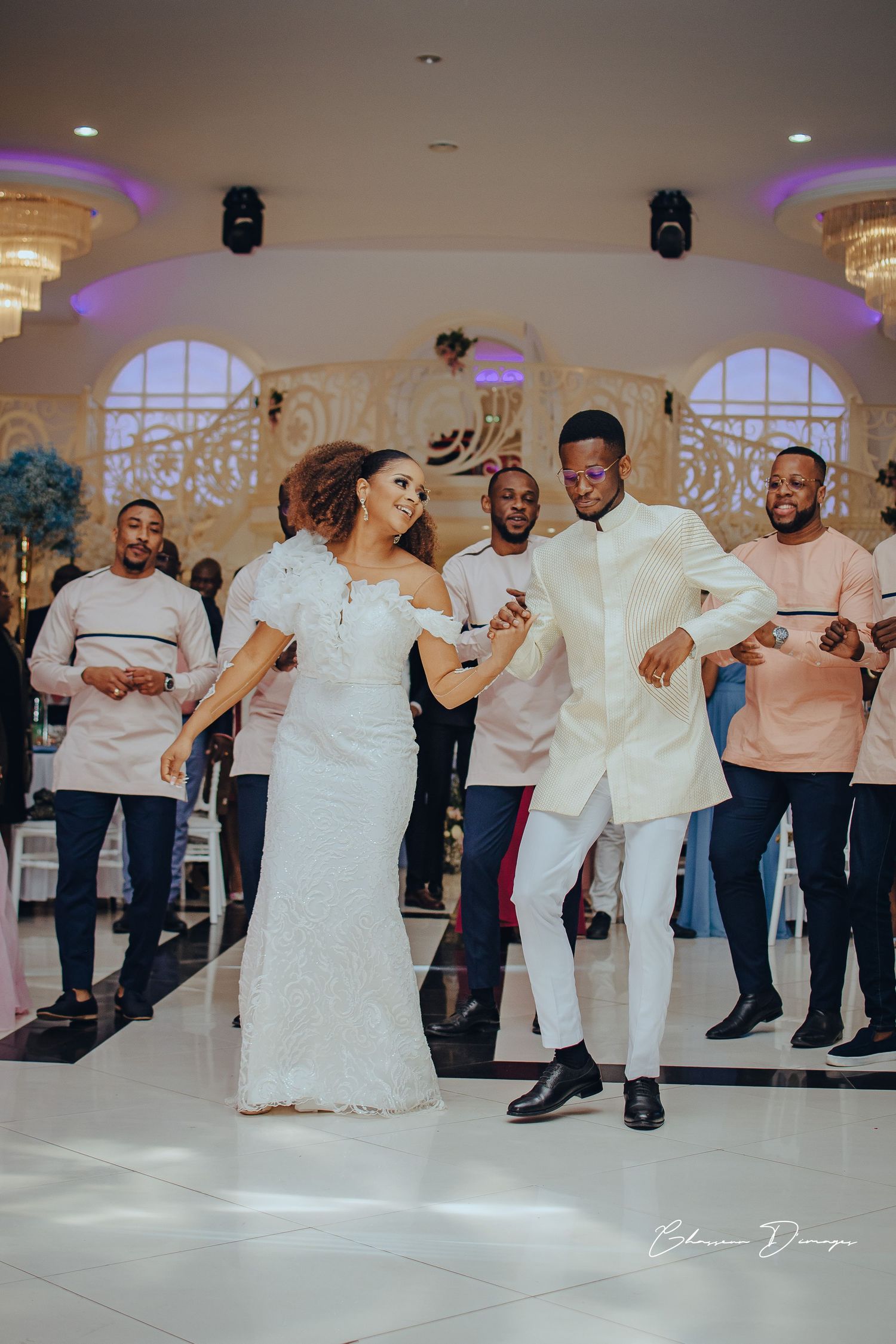 Lively wedding dance celebration in elegant ballroom with purple mood lighting.