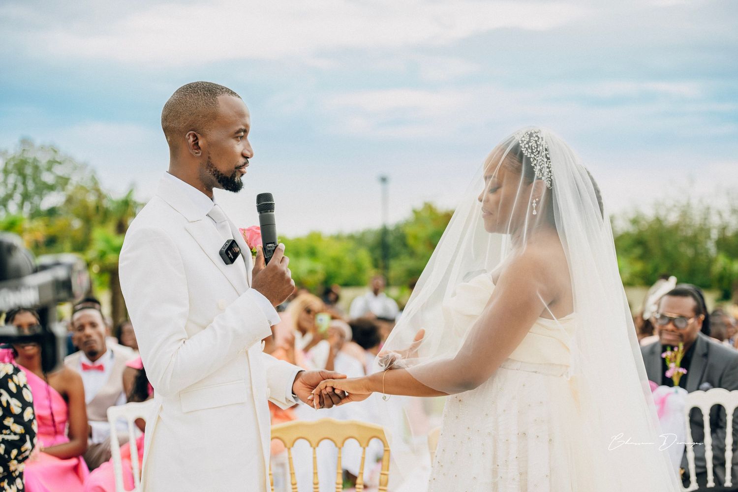 Couple holds hands during emotional outdoor wedding ceremony.
