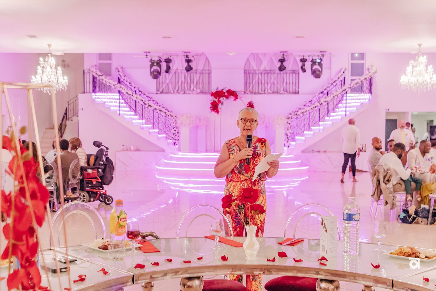 Wedding venue with dramatic pink and purple lighting, stairs, and scattered rose petals.