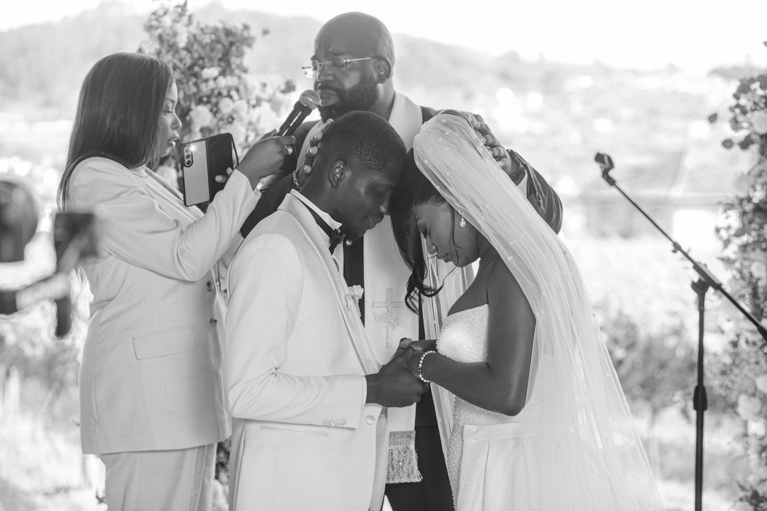 An emotional black and white moment captured during a wedding ceremony with multiple people embracing.