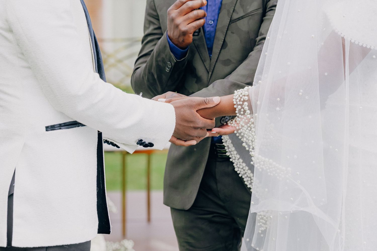 Wedding ceremony attendees in formal white and dark attire standing together.
