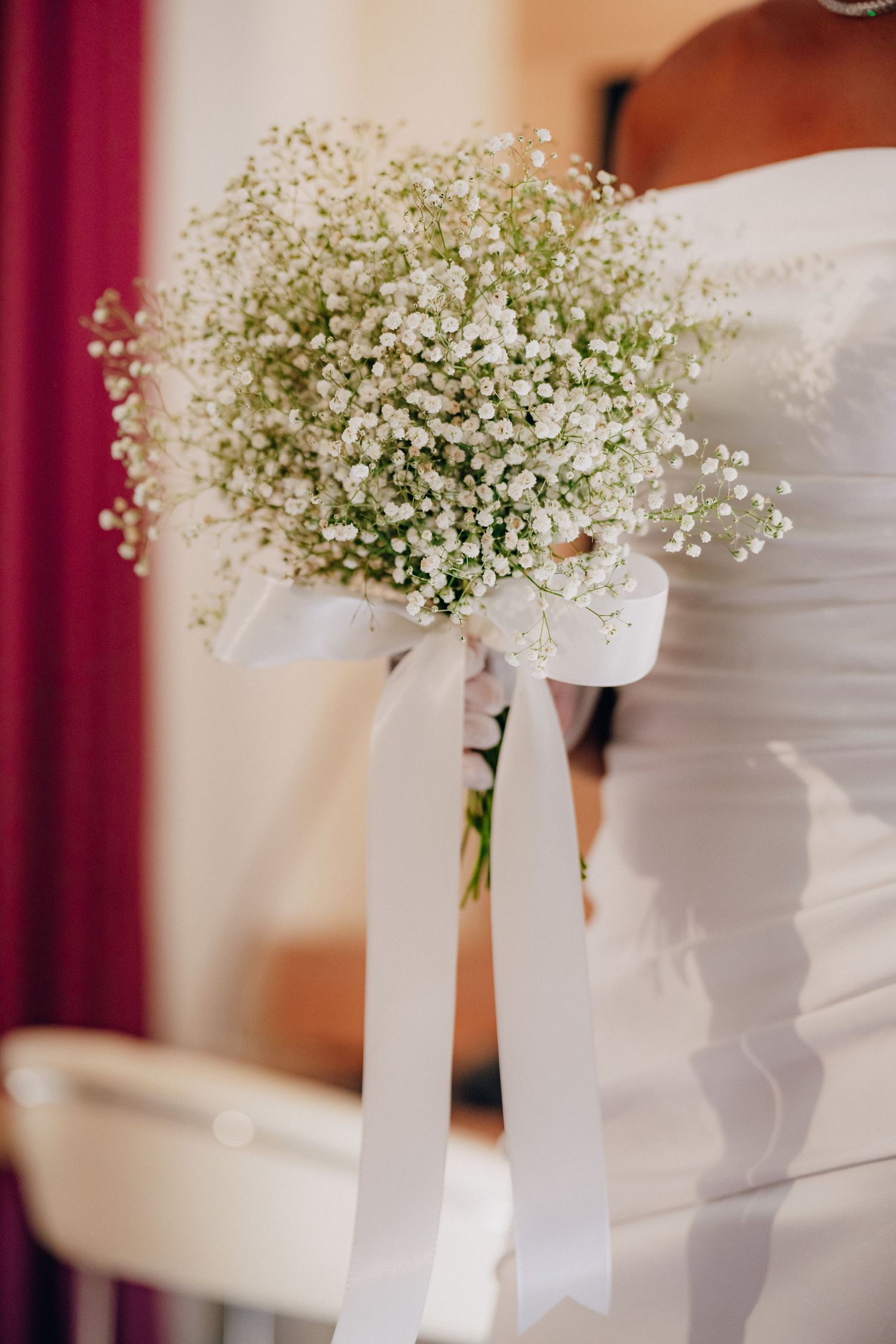 Baby's breath flowers in white vases with ribbons arranged in a line for wedding decor.