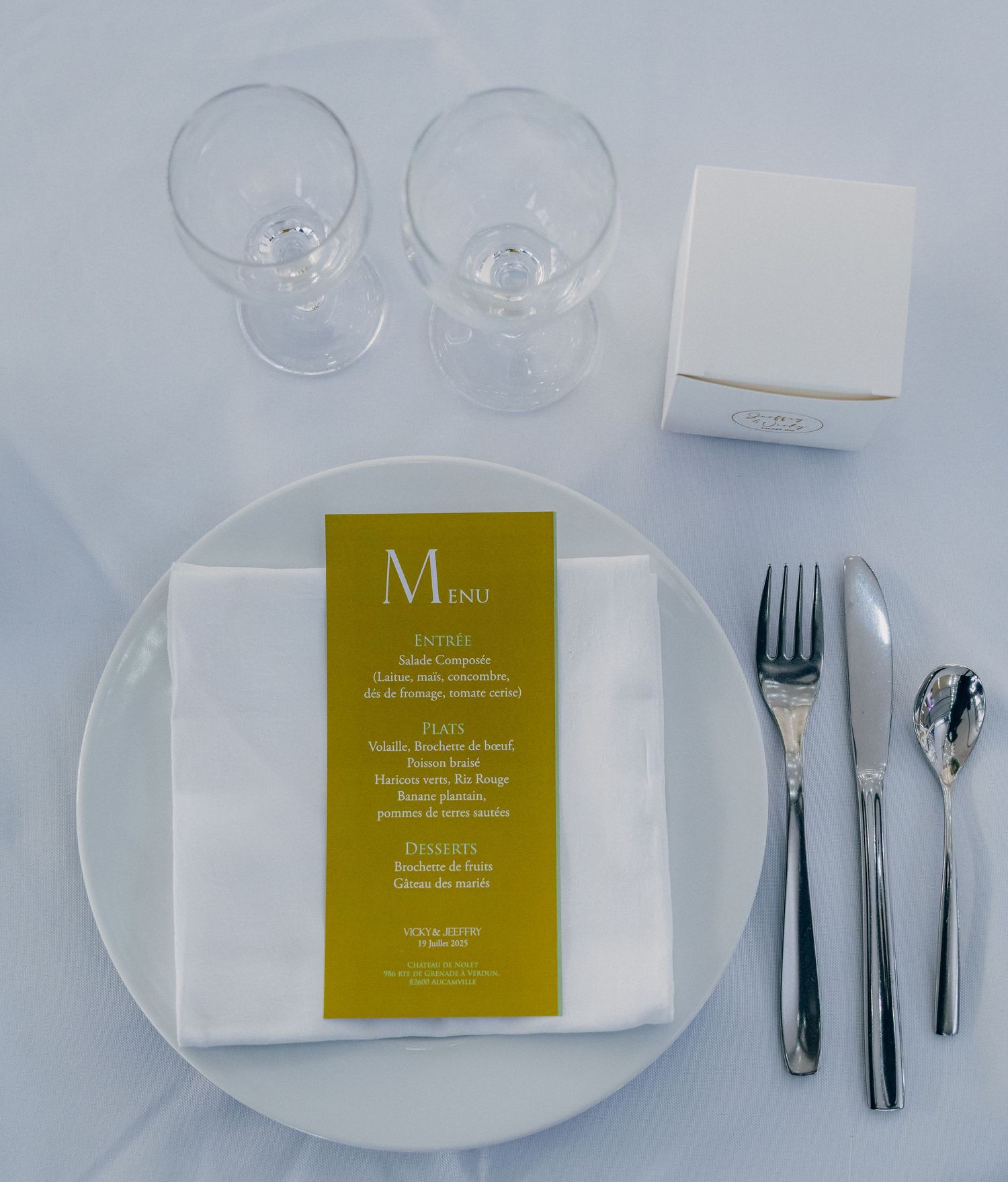 Elegant place setting at a formal dinner with wine glasses, white plates, and gold menu cards.