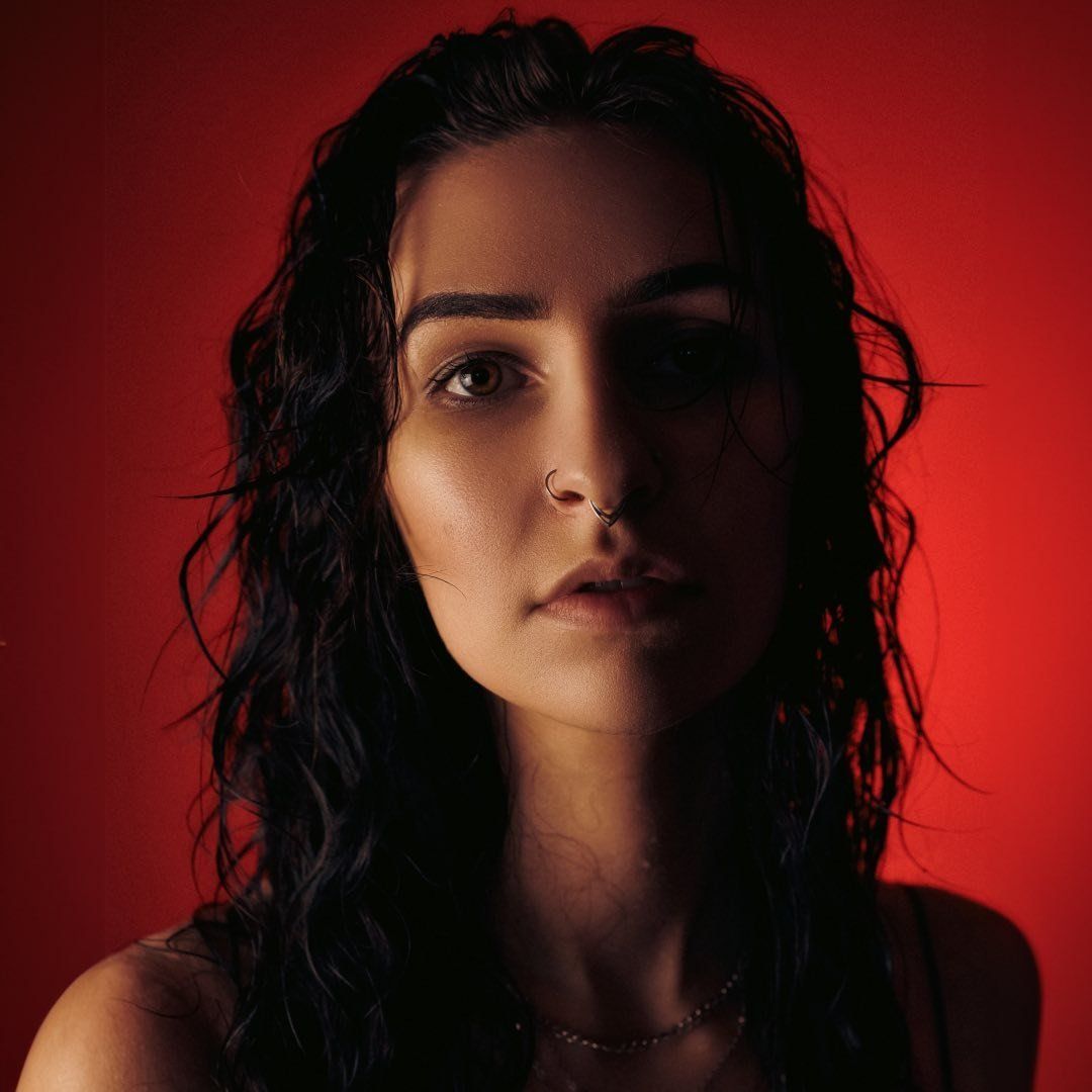 Dramatic portrait series with dark curly hair against deep red background showing different angles in moody lighting.