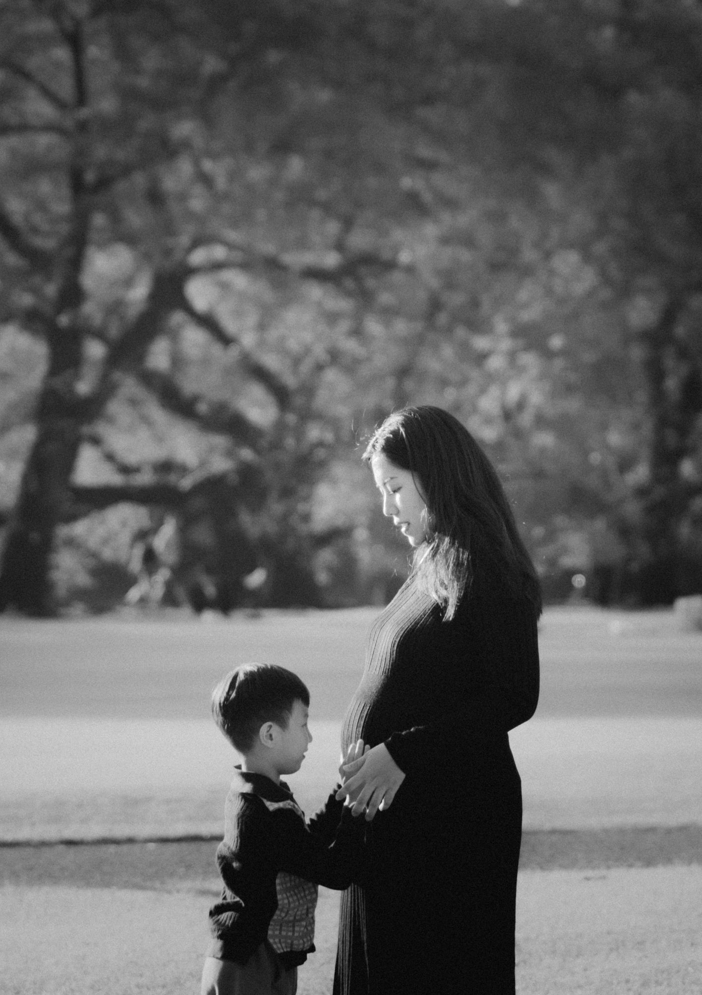Black and white portrait of mother and child standing together outdoors.