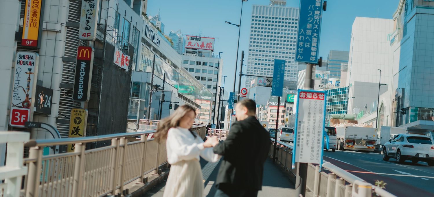 Couple walking on urban street with modern cityscape backdrop in Japan.