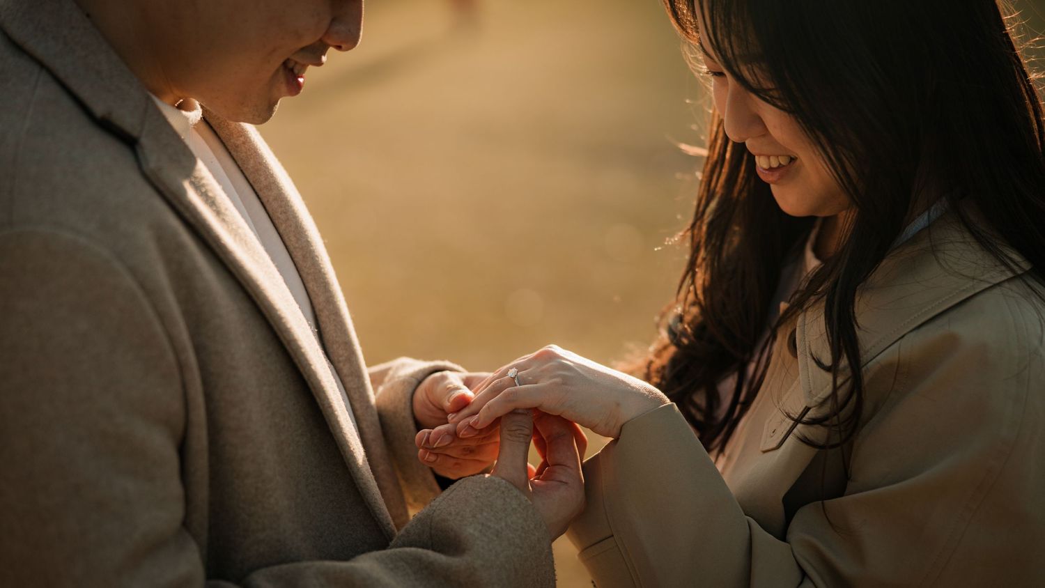 Intimate moment captured as couple exchanges rings in warm lighting.