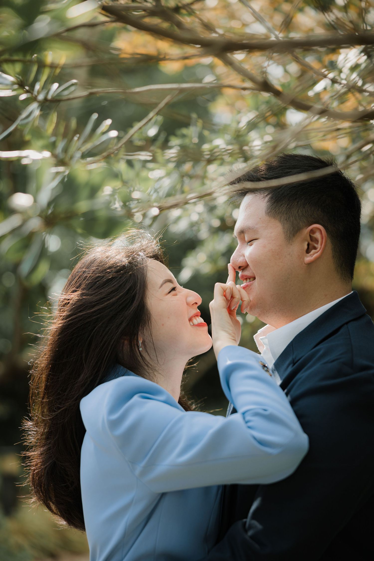 Romantic couple in blue and navy outfits sharing tender moment outdoors.