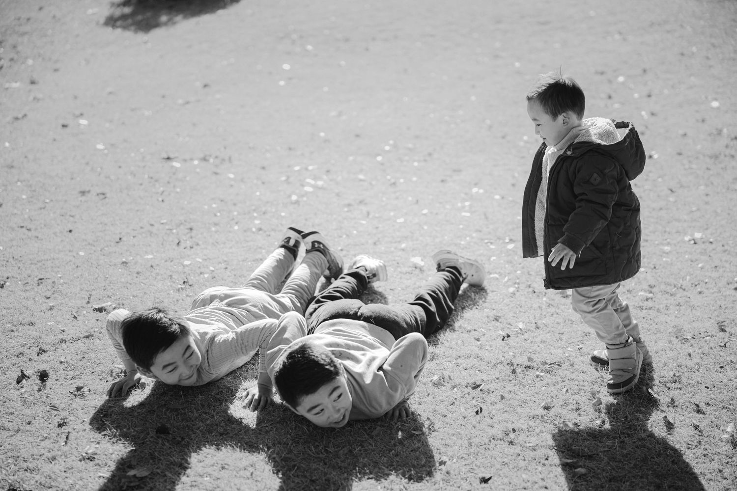A black and white photo of people playing and lying in the sand.