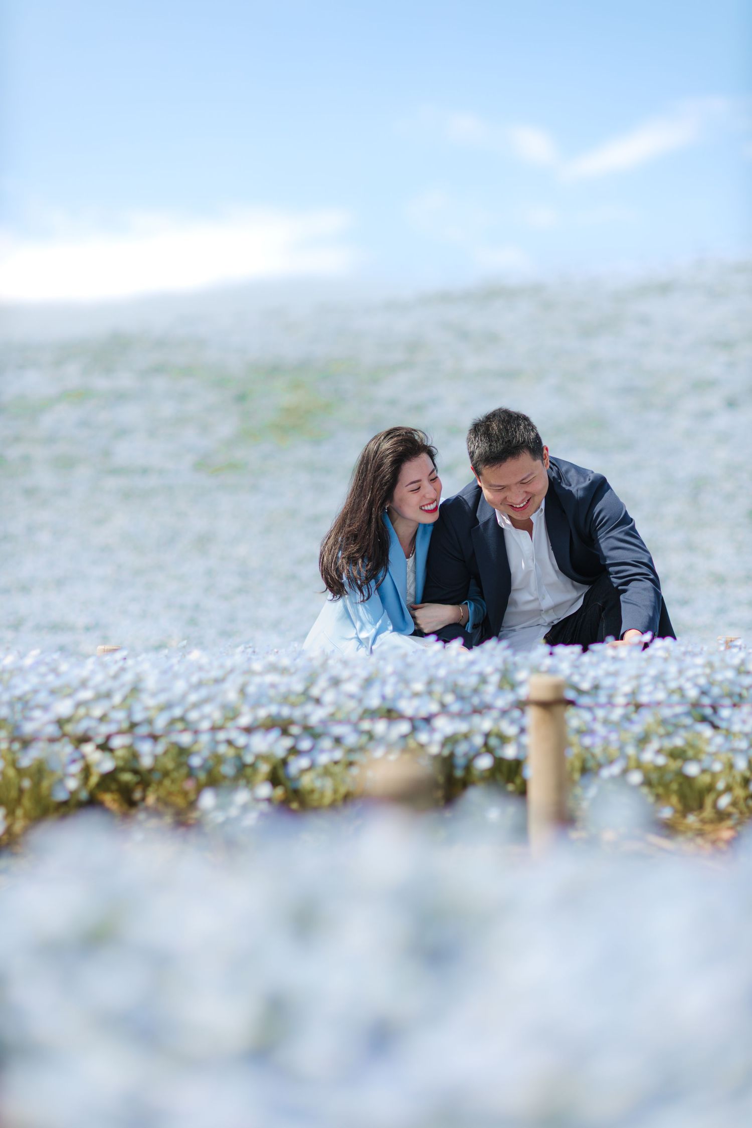 Couple sharing intimate moment among blooming blue flowers on hillside.