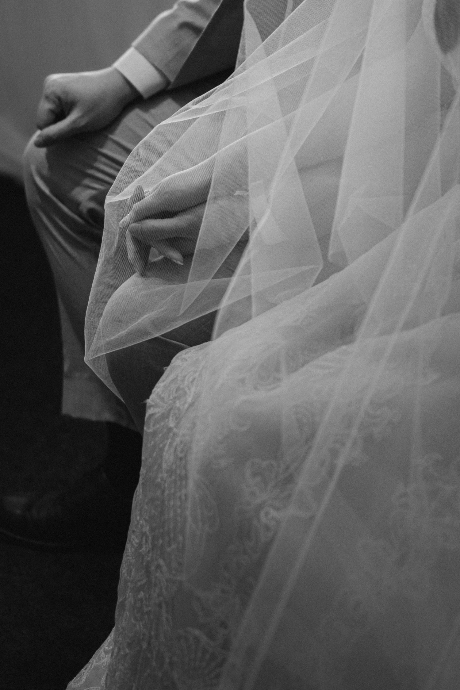 Close-up detail shot of delicate bridal veil lace and fabric in black and white.