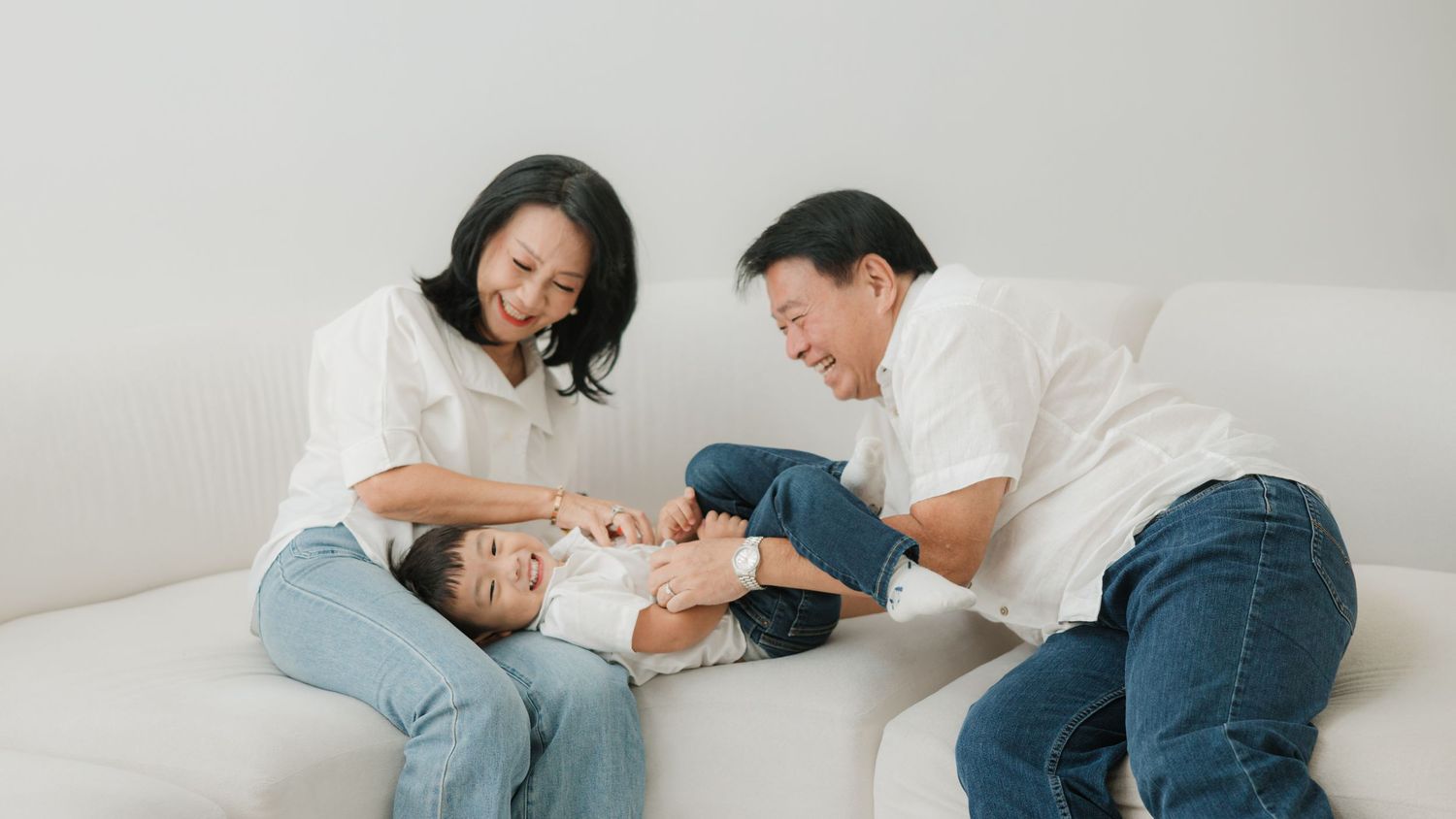 A playful moment shared on a white couch in a bright, airy room.