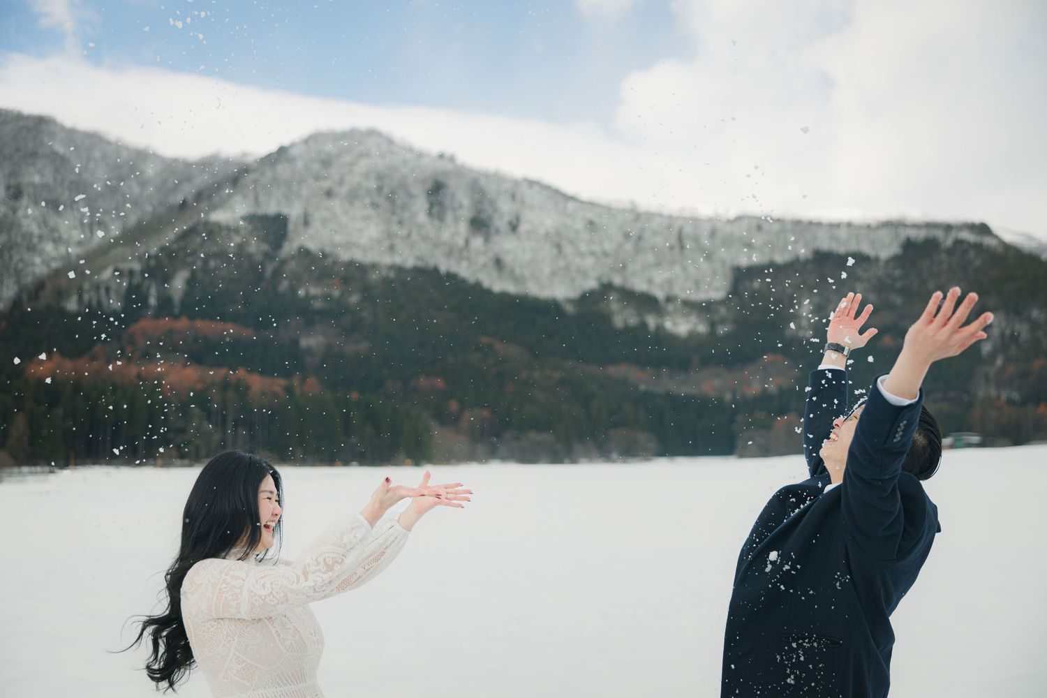 Playful winter scene with snow being thrown against a mountainous backdrop.