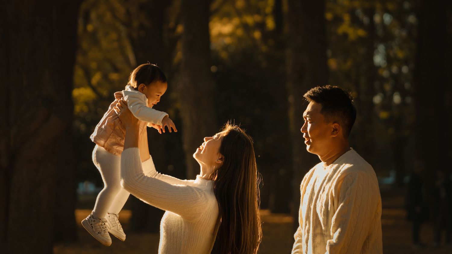 Family of three sharing a tender moment outdoors at sunset.