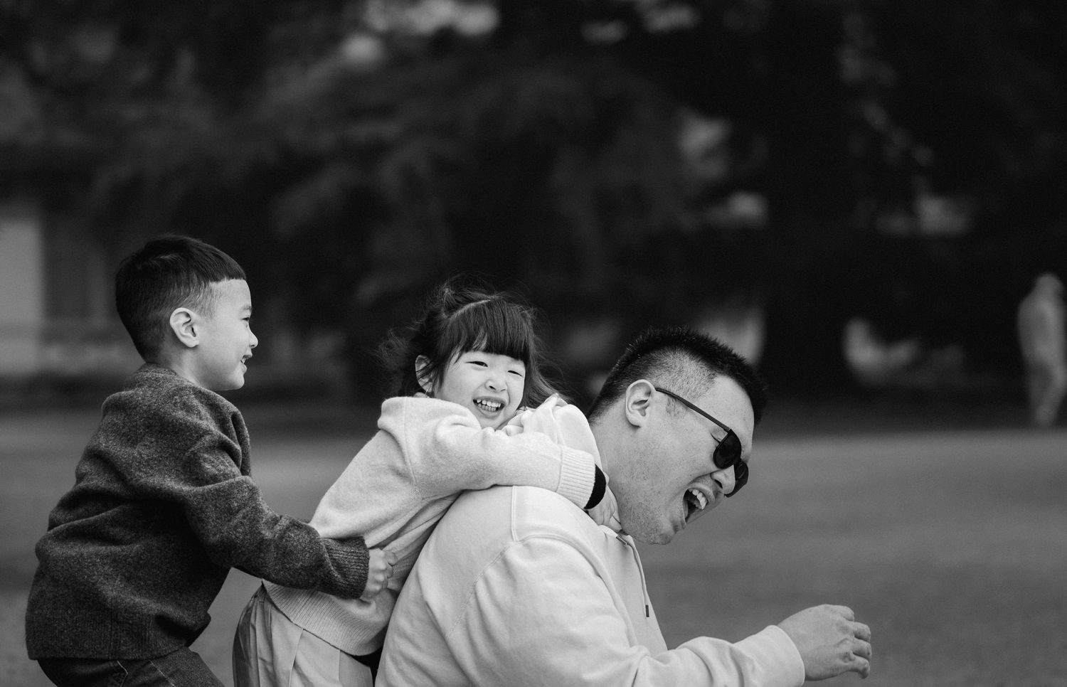 Black and white photo of playful family moment in a park.