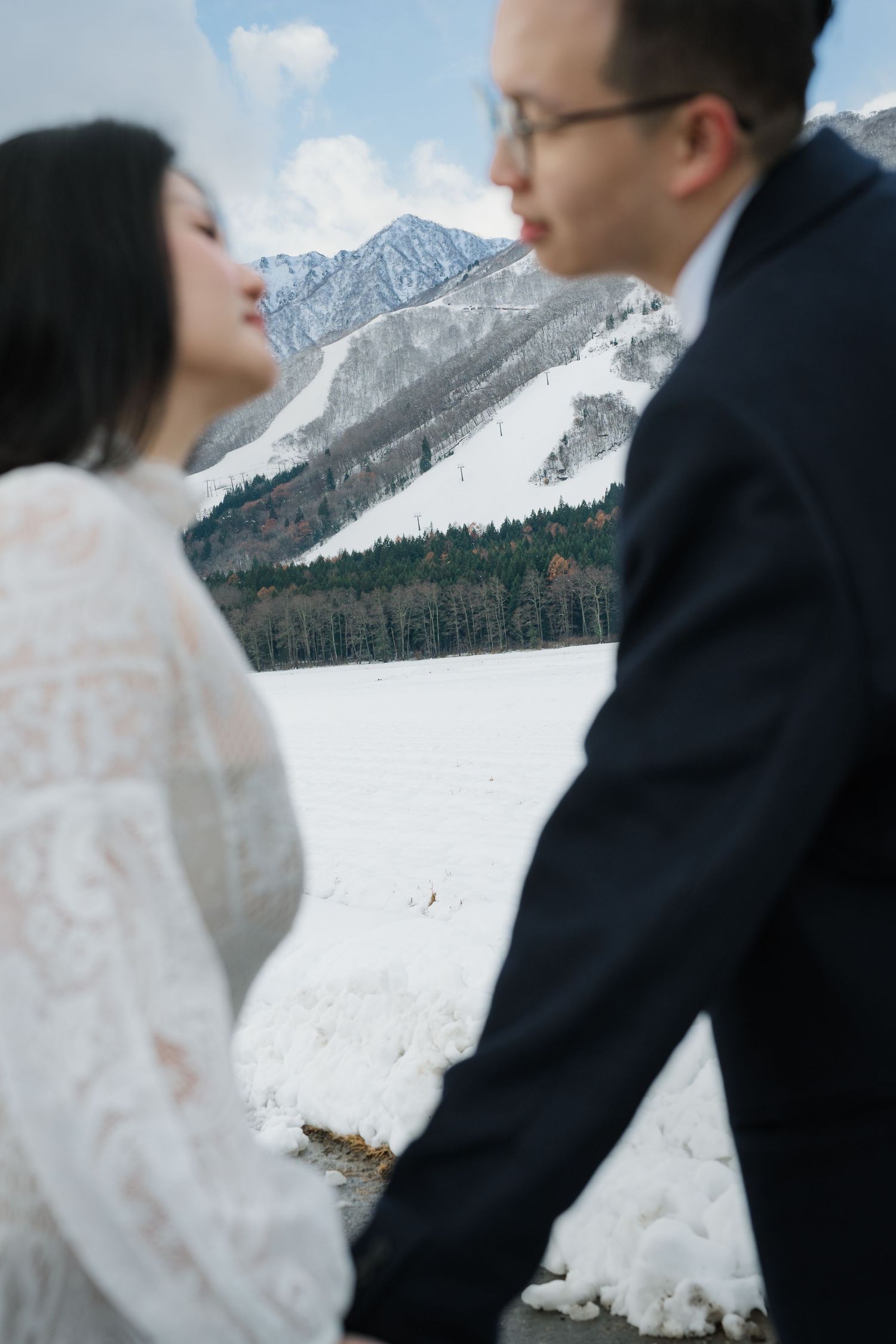 A romantic moment captured against a backdrop of snow-covered mountains and winter scenery.