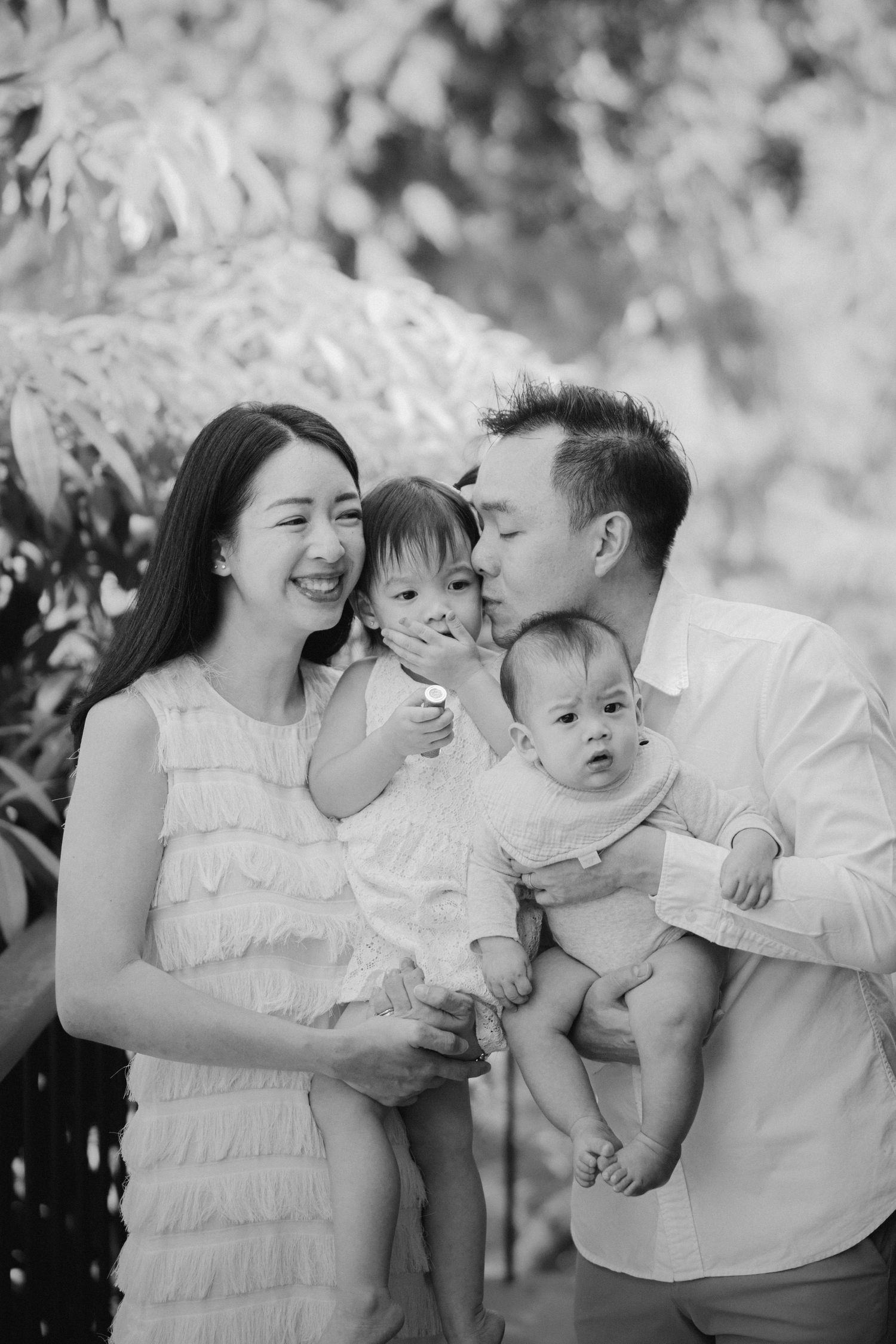 Family sharing intimate moment outdoors in black and white photography.
