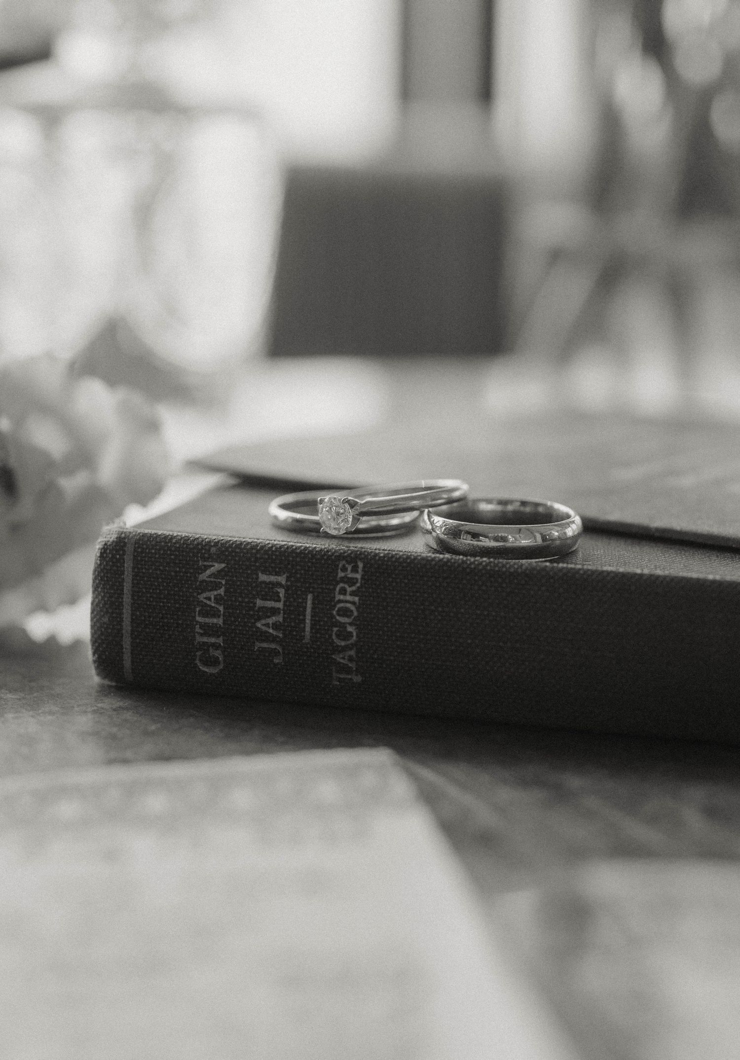 Two wedding rings resting on a vintage copy of Gitanjali by Tagore in black and white.