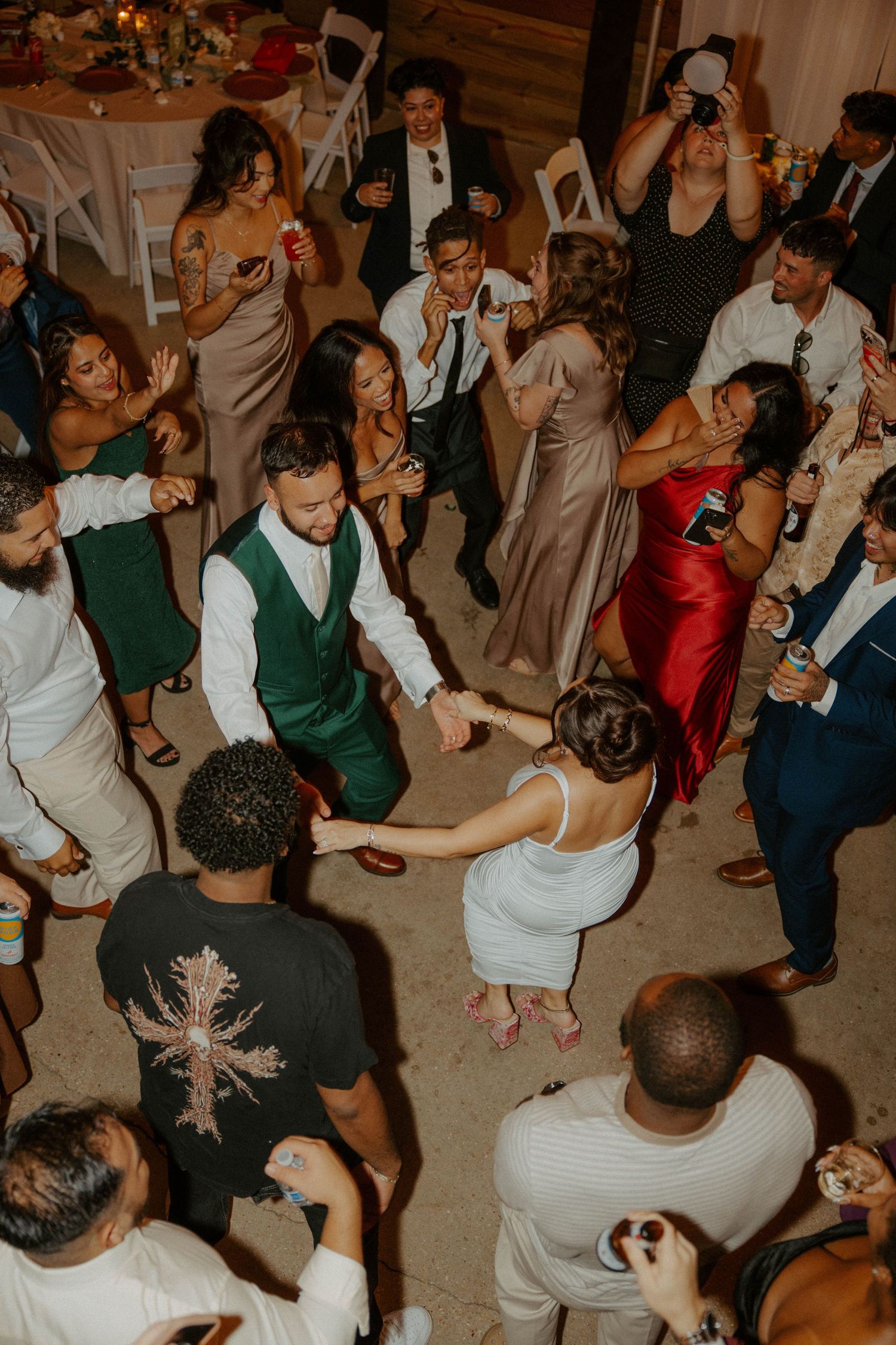 Overhead view of bride groom and guests dancing together at lively wedding reception.