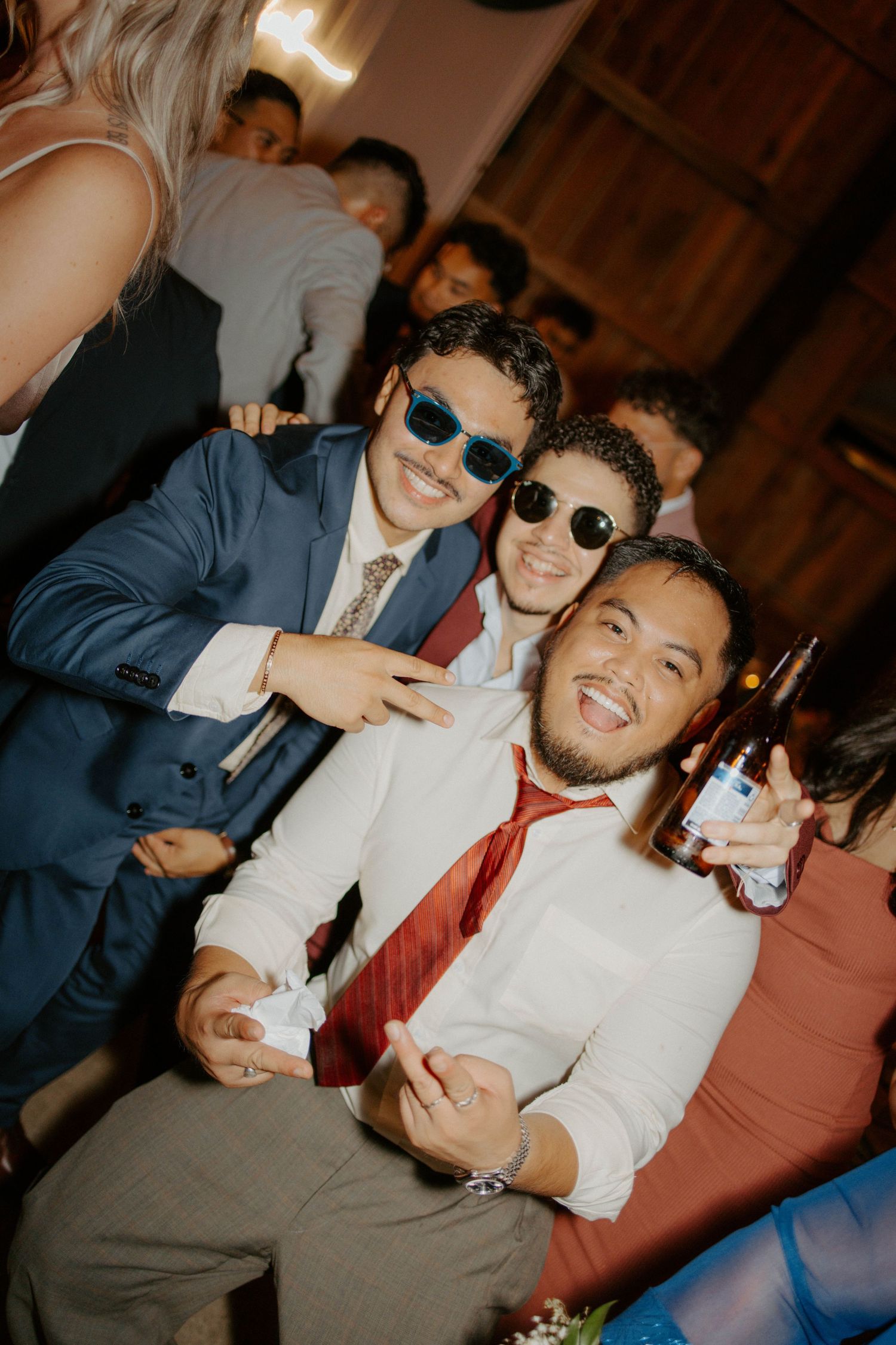 Two wedding guests in sunglasses smiling and posing at lively reception party.