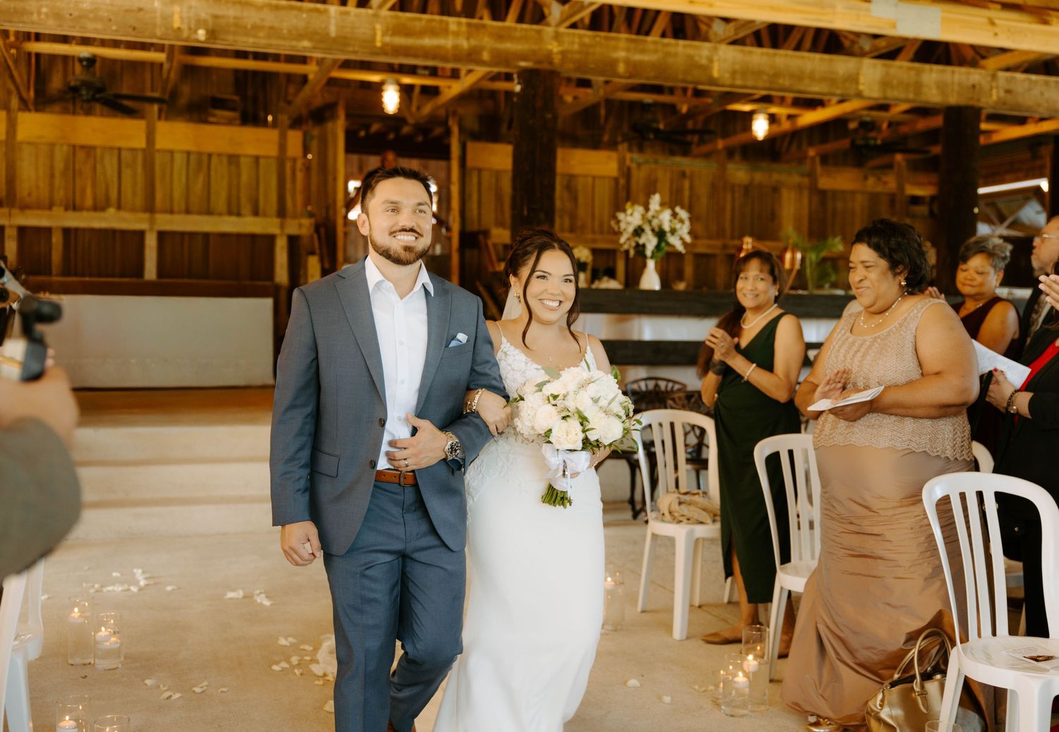 Joyful newlyweds walking back down the aisle in a rustic barn wedding ceremony.