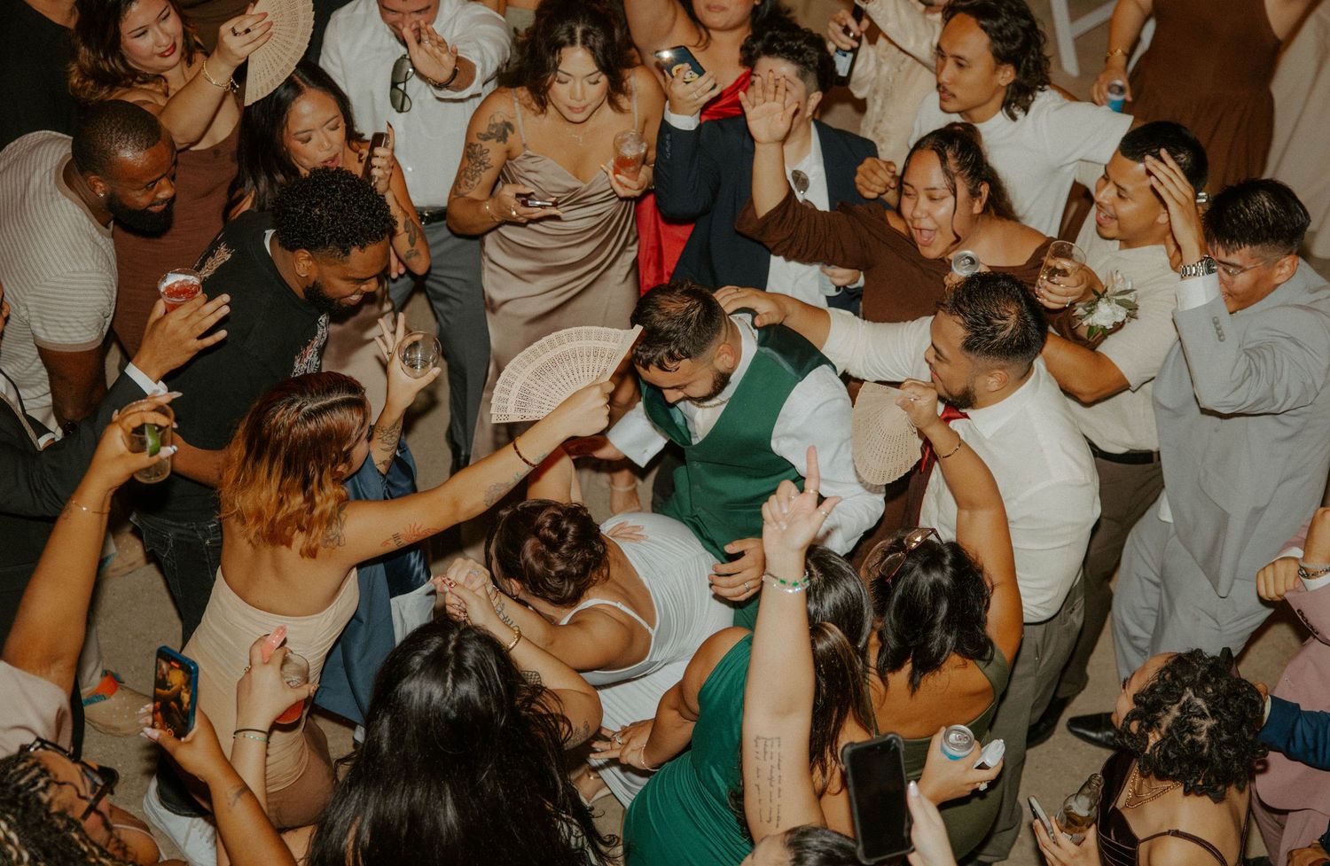 Aerial view of wedding guests crowding the dance floor during a lively reception celebration.