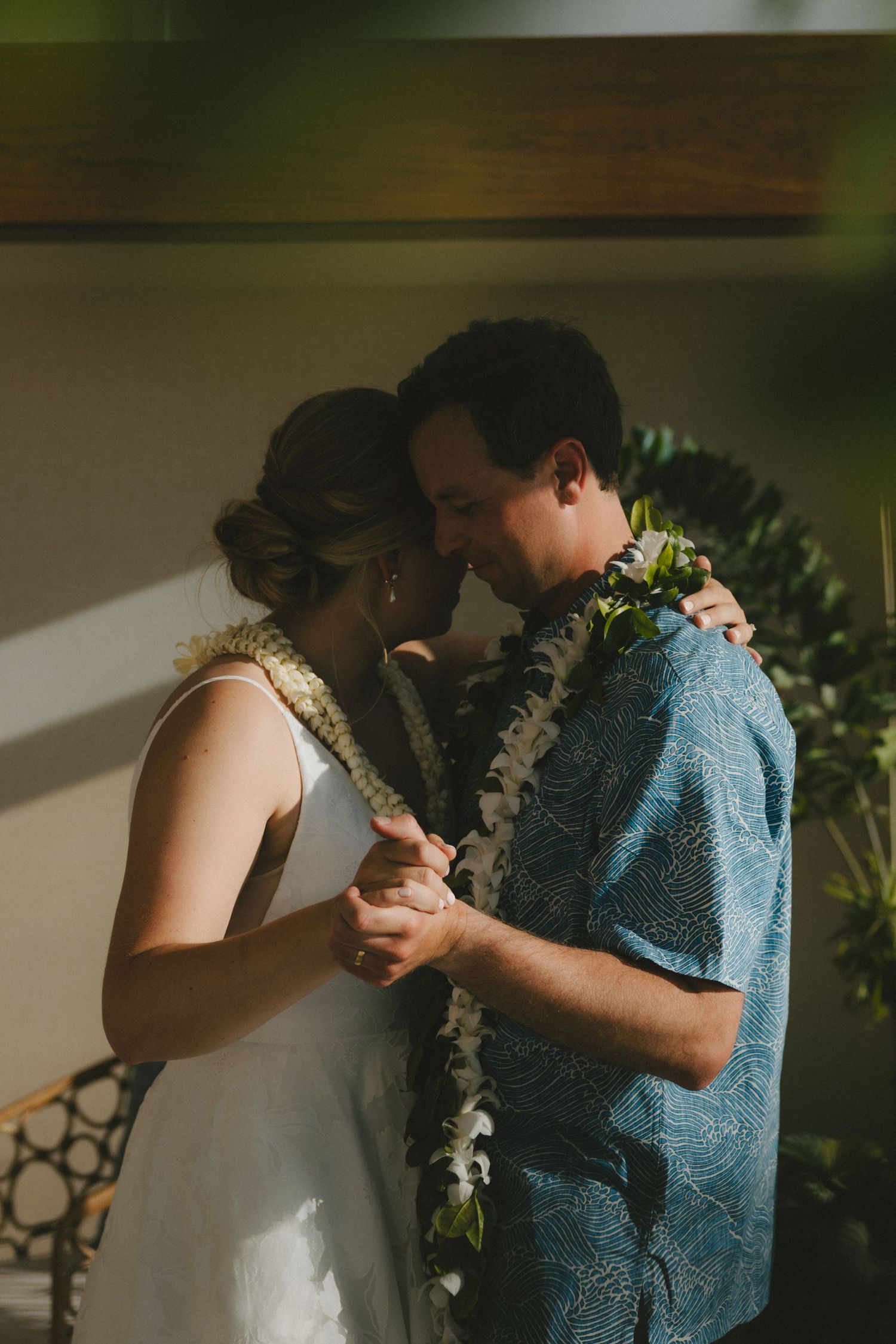 Couple in a warm intimate moment during their wedding reception, the groom and bride slow dancing together as the sunlight softly hits them