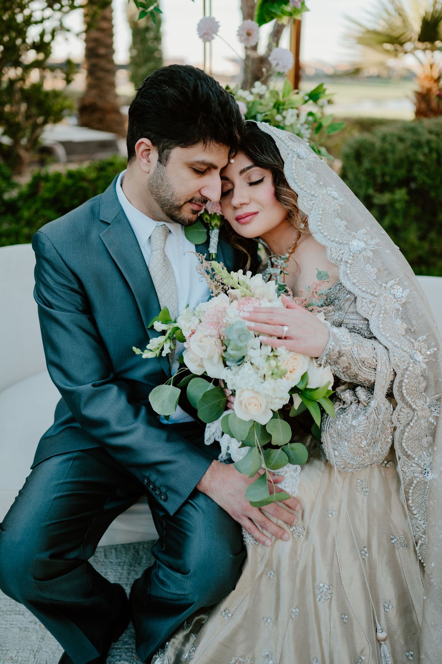 Close-up romantic portrait of a couple sharing an intimate moment on their wedding day with a beautiful bouquet and lace veil.