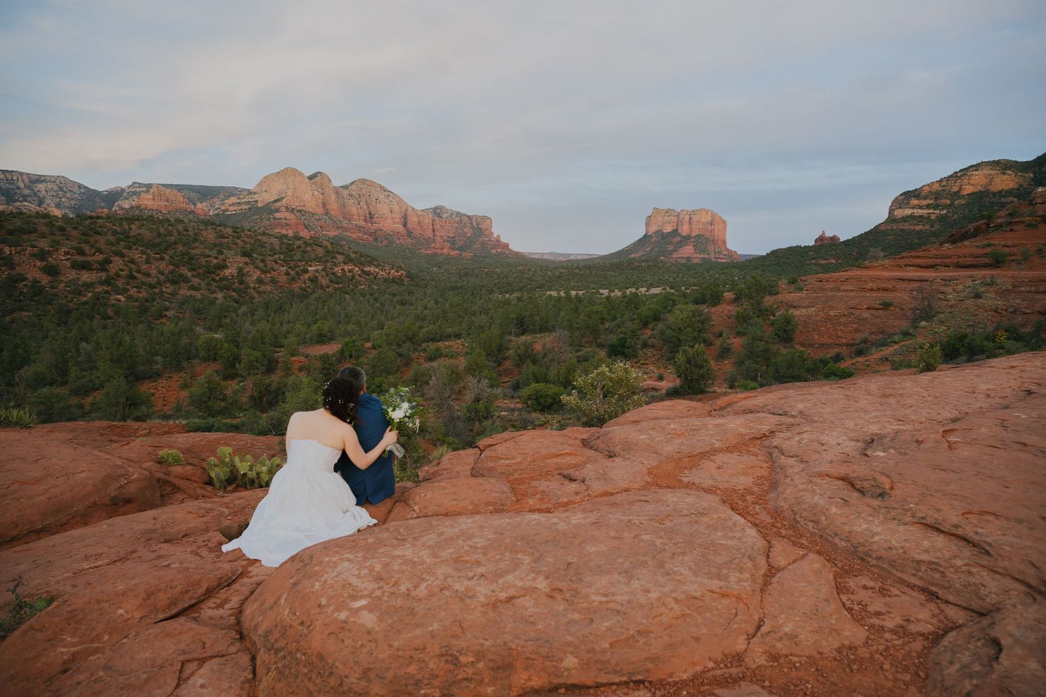 A stunning sunset wedding photo session captured on the red rocks of Sedona with Cathedral Rock in the distance.