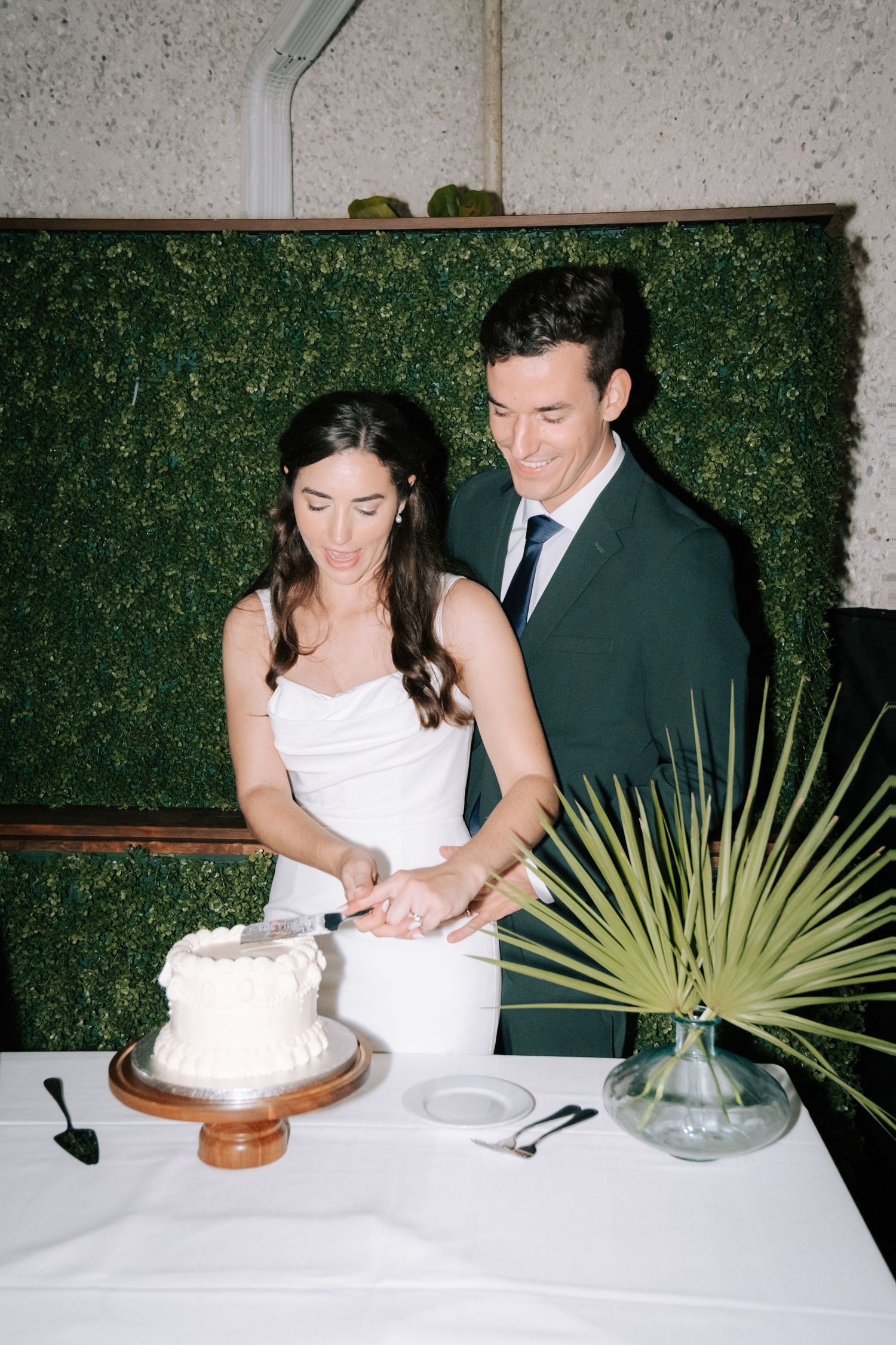 Newlyweds cut their wedding cake together at an elegant reception.