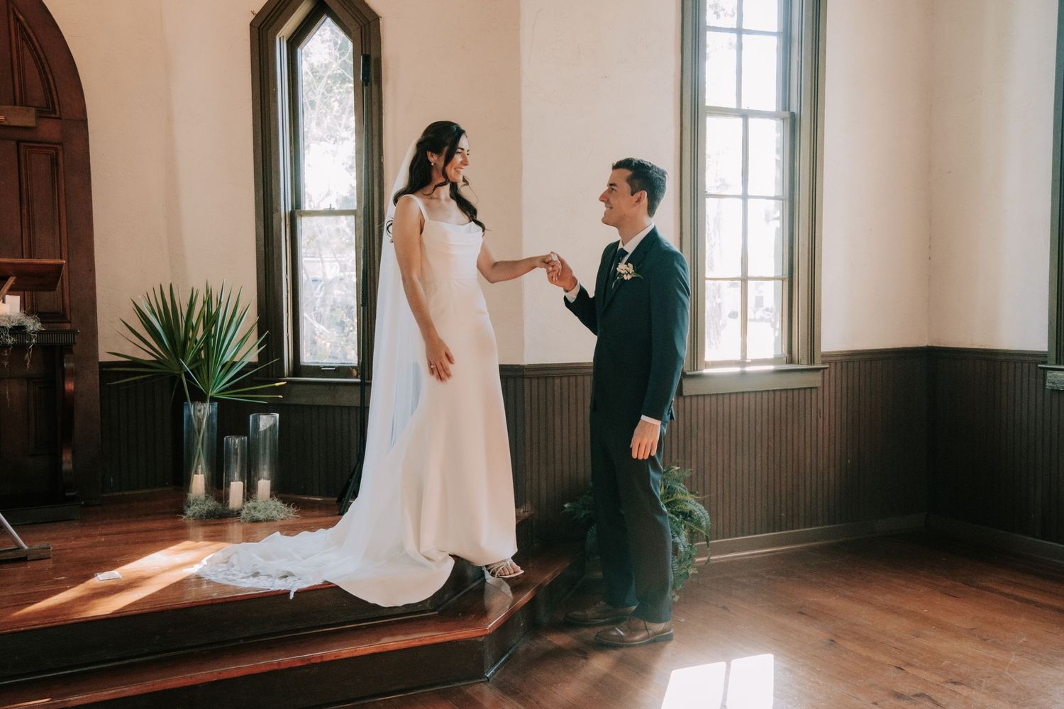 Elegant wedding couple dancing and twirling in a historic chapel with arched windows.