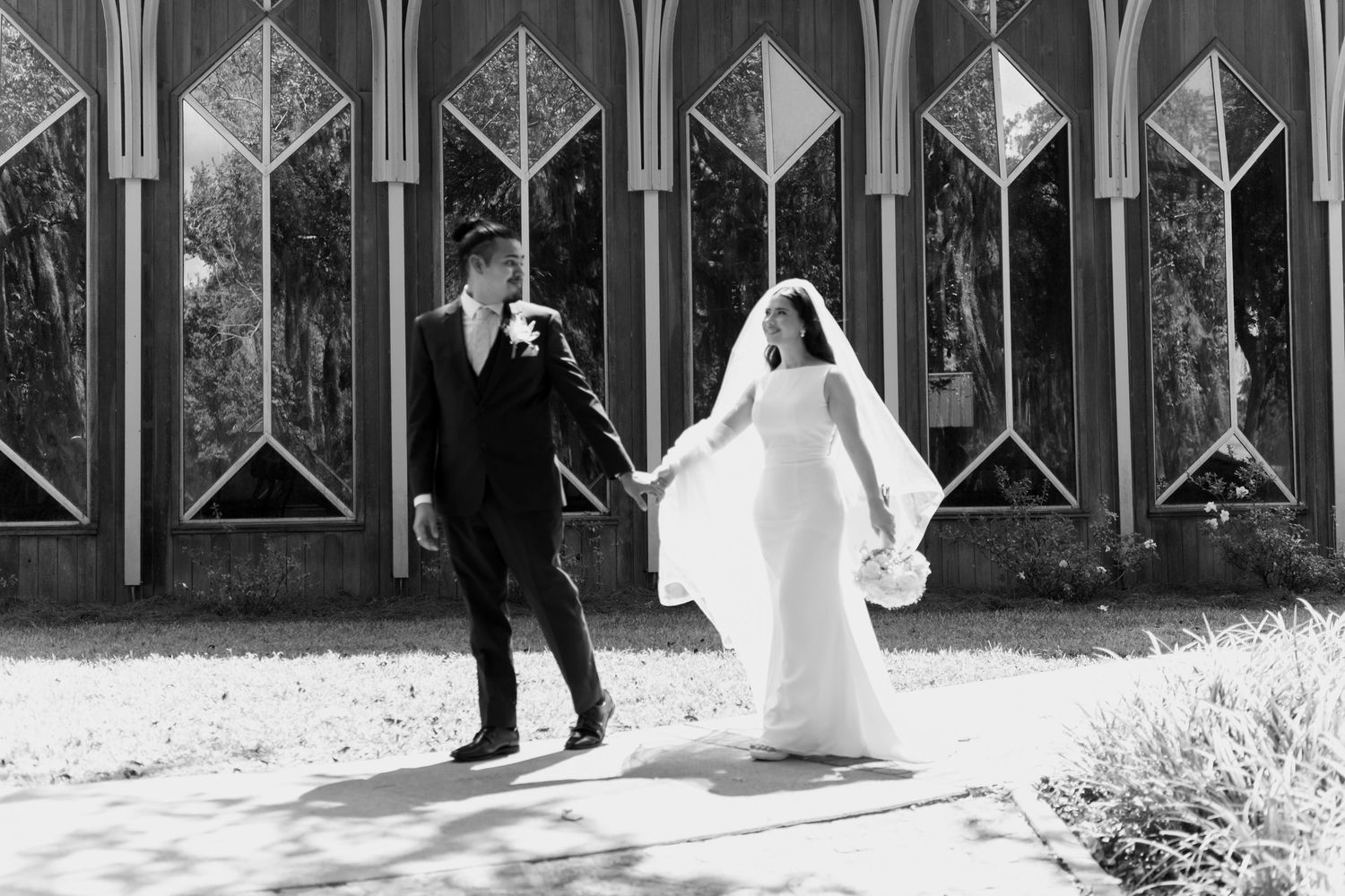 Black and white panorama of wedding couple in architectural setting.