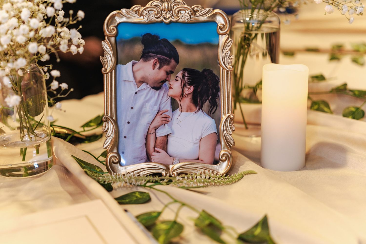 Wedding reception details with vintage frames and delicate floral arrangements on a wooden table.