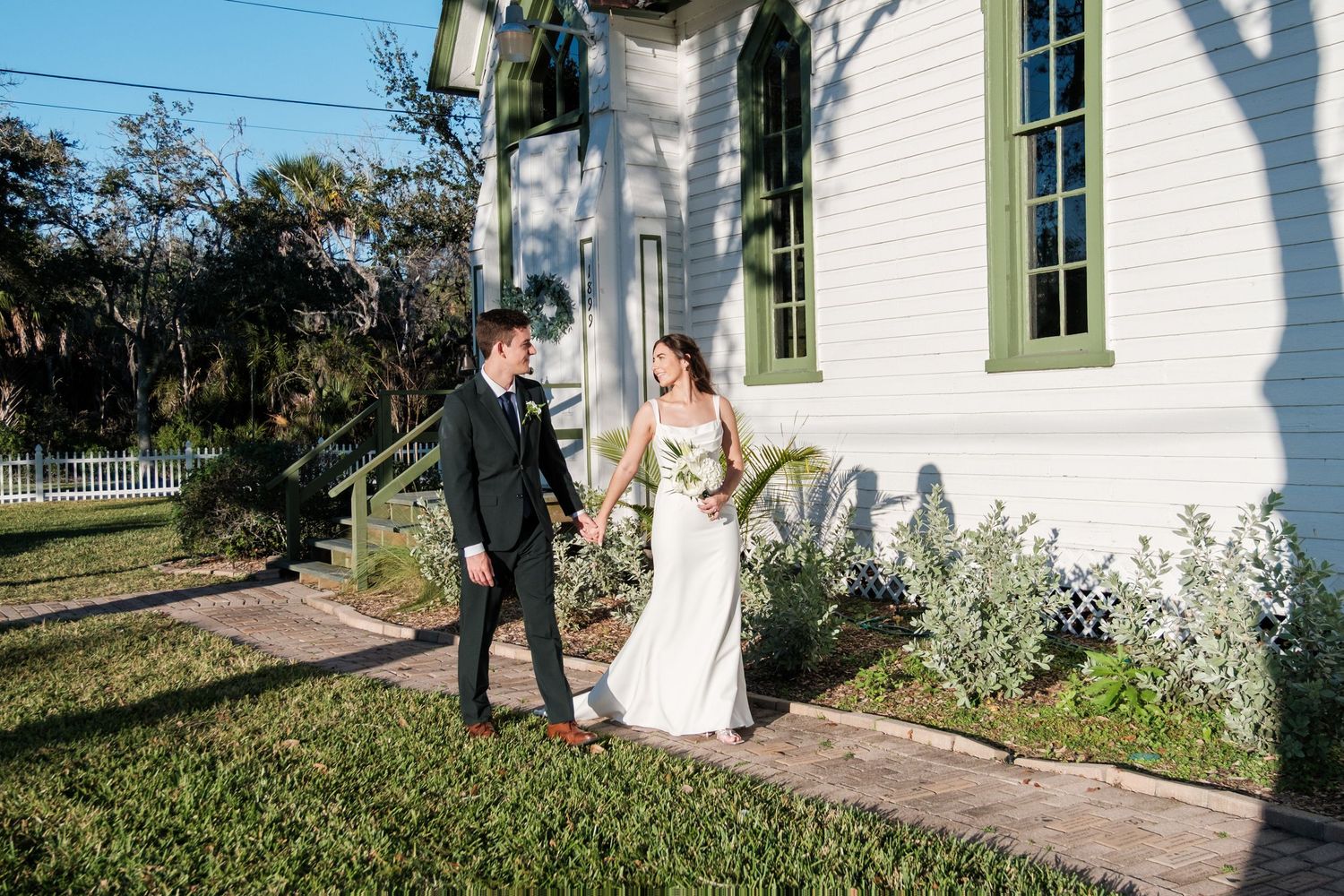 Wedding ceremony setting outside a charming white chapel with green trim.
