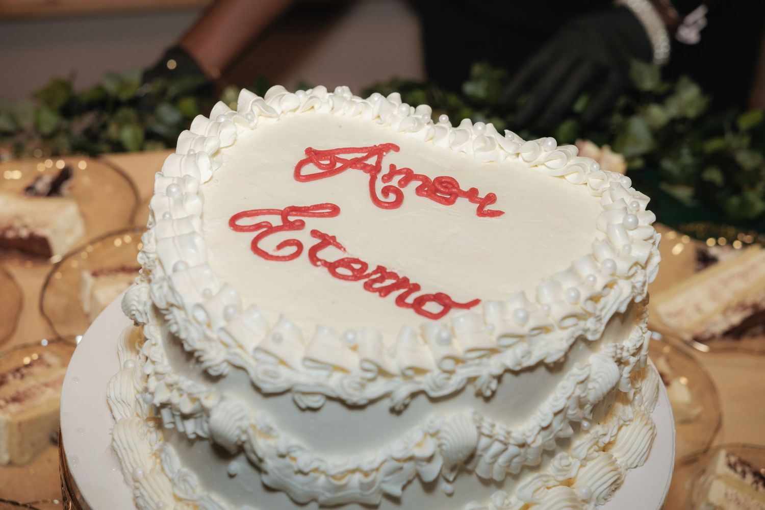 Close-up view of a white wedding cake with red decorative writing on top.