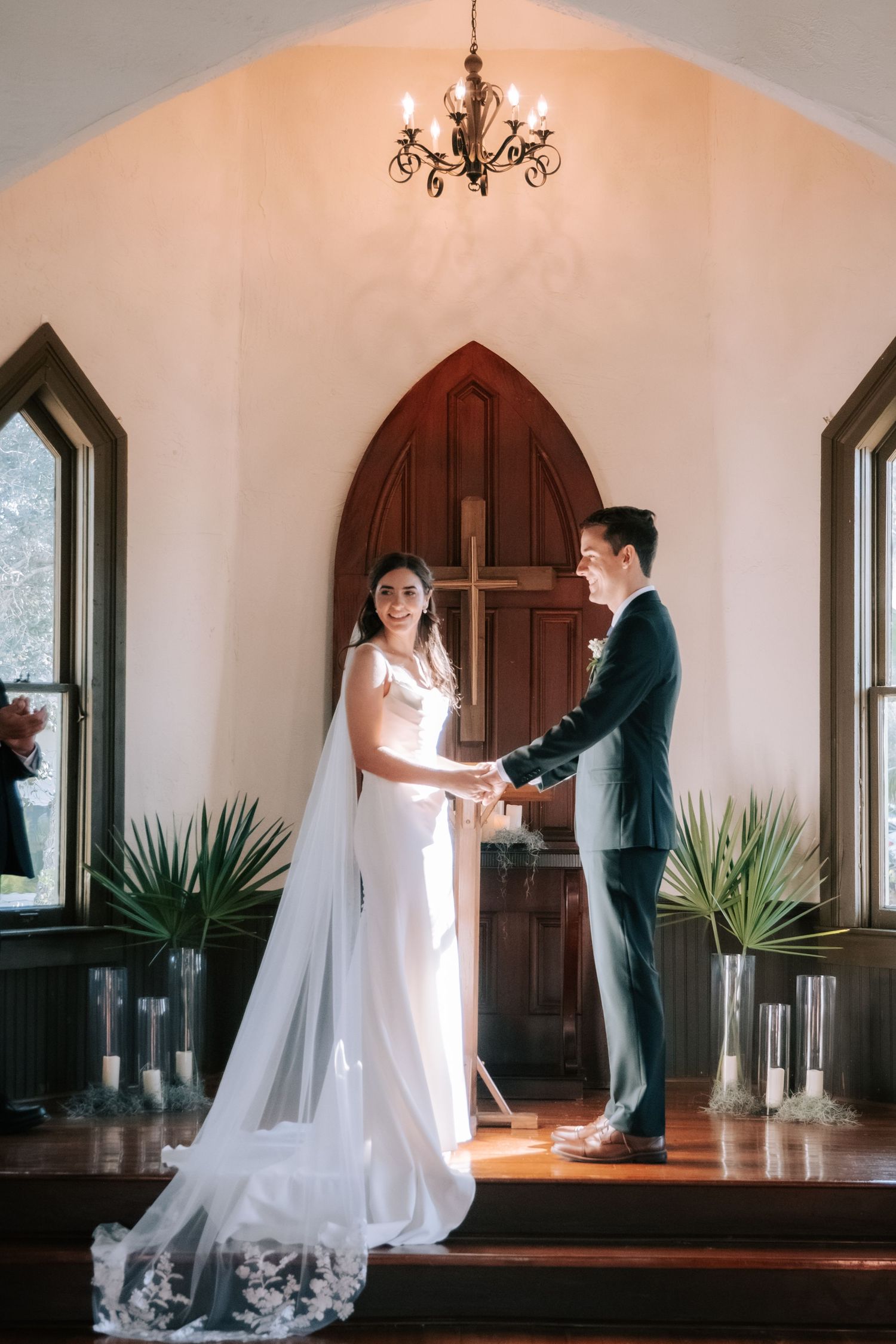 Romantic first dance in a white chapel interior with gothic windows and potted plants.