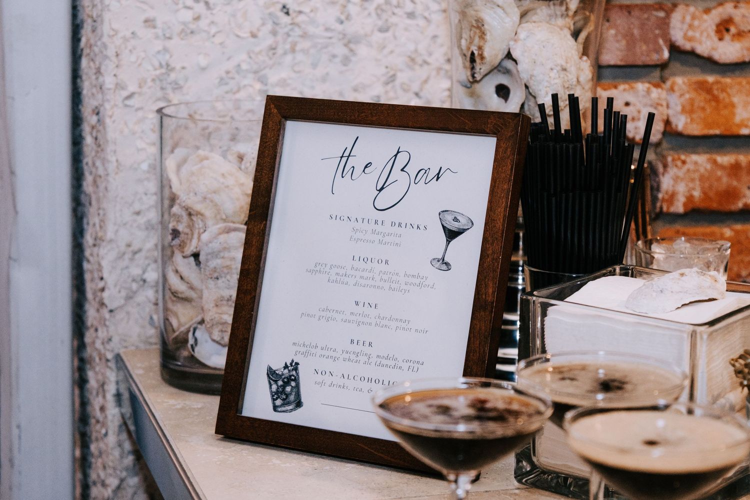 Rustic bar menu signs displayed on exposed brick wall at wedding reception.