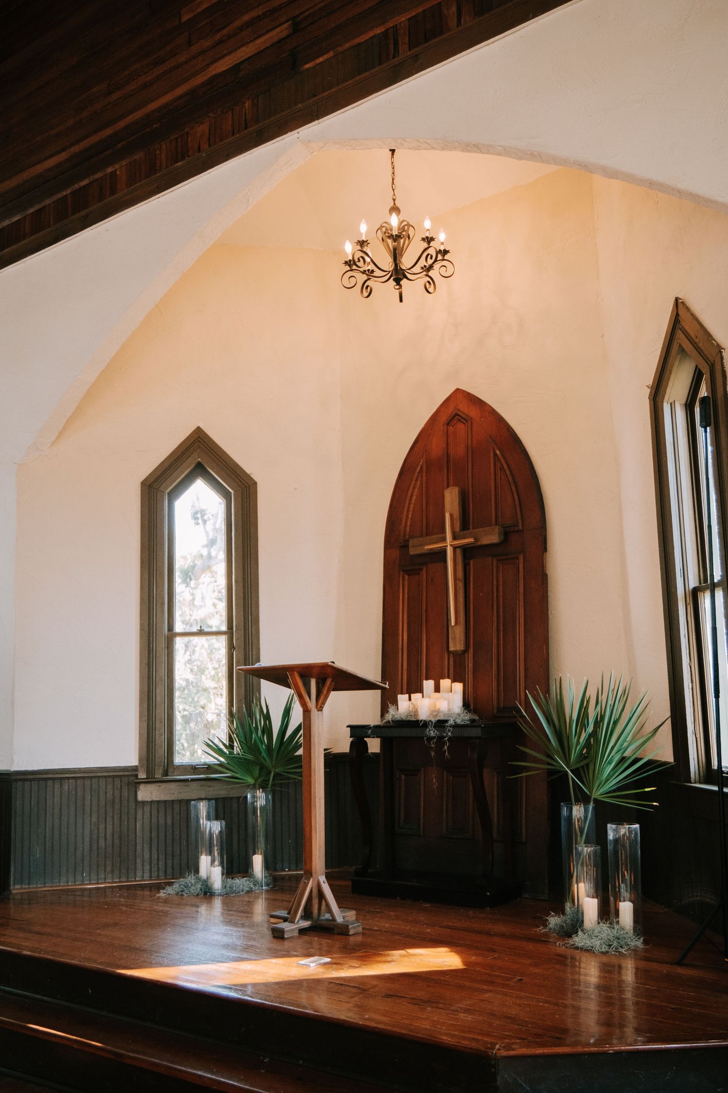 Interior of a historic church with arched windows, wooden floors, and gothic architectural details.