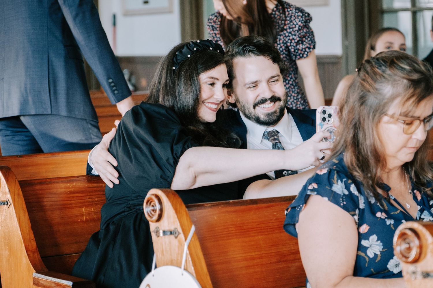 People sharing a joyful moment while sitting together in wooden church pews during a gathering.