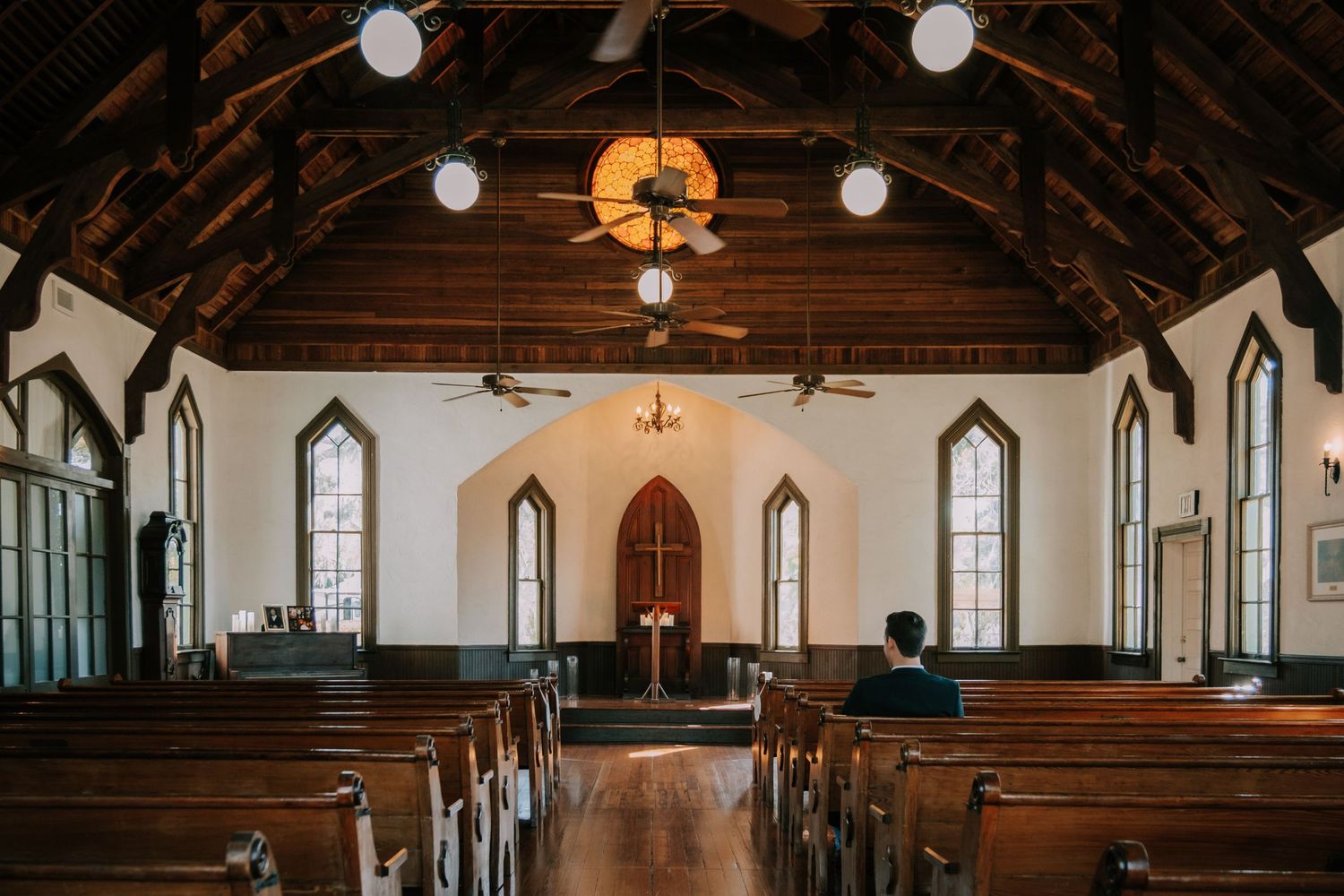 Interior of historic chapel with wooden beams and gothic windows.